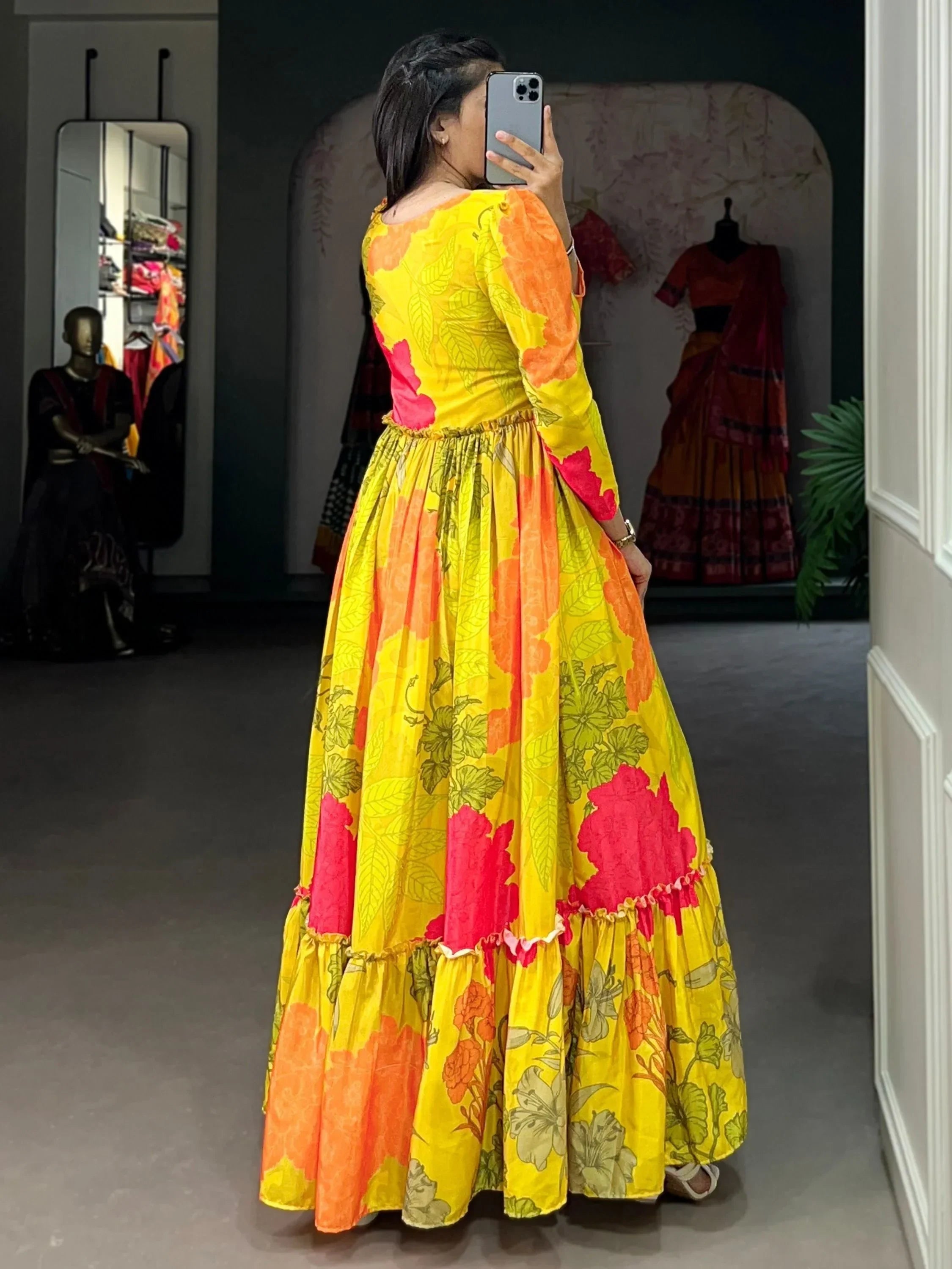 Woman wearing yellow floral ethnic gown with orange and pink patterns, side view