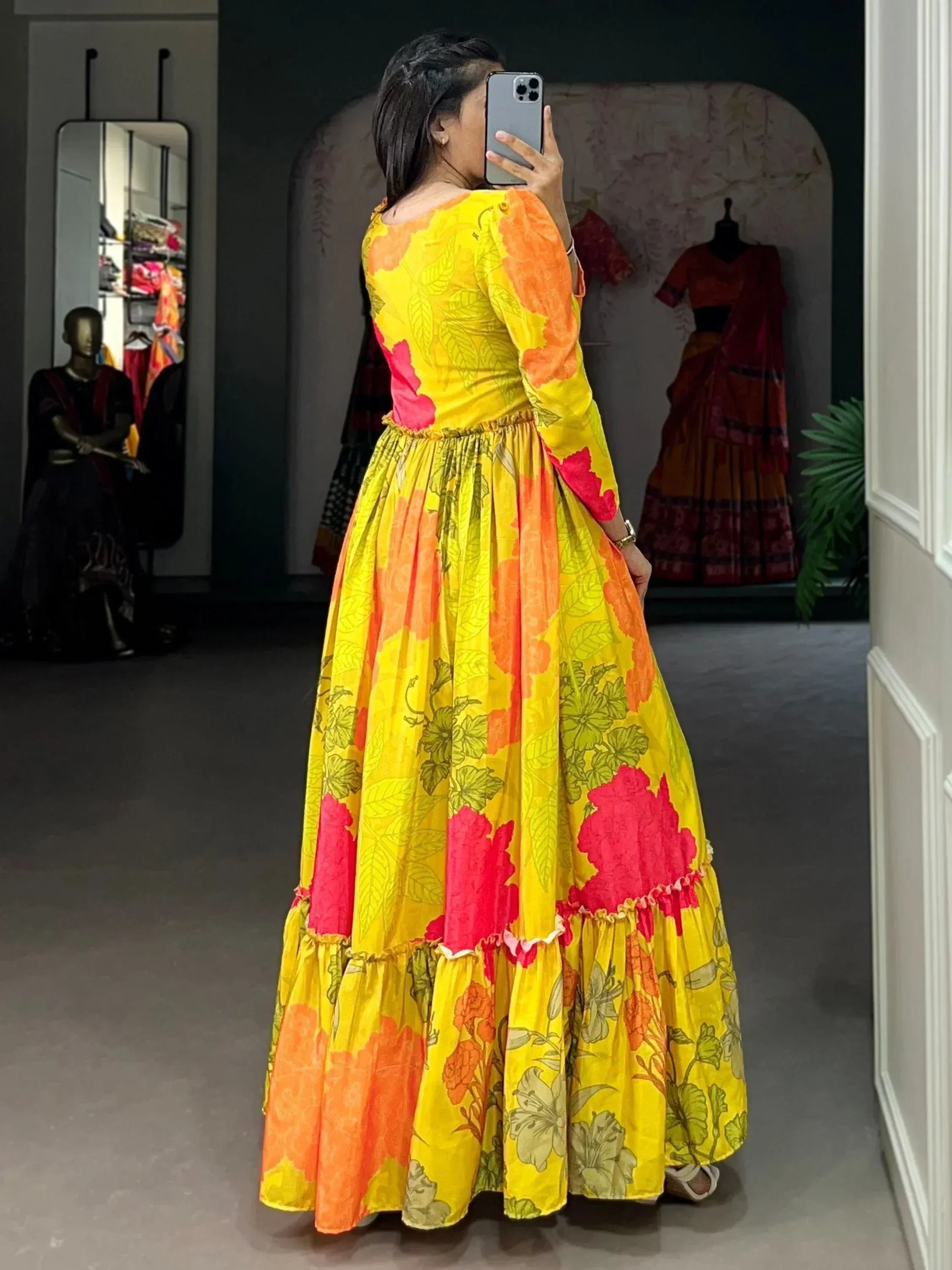 Vibrant yellow floral ethnic gown with orange and pink accents, perfect for festive occasions.