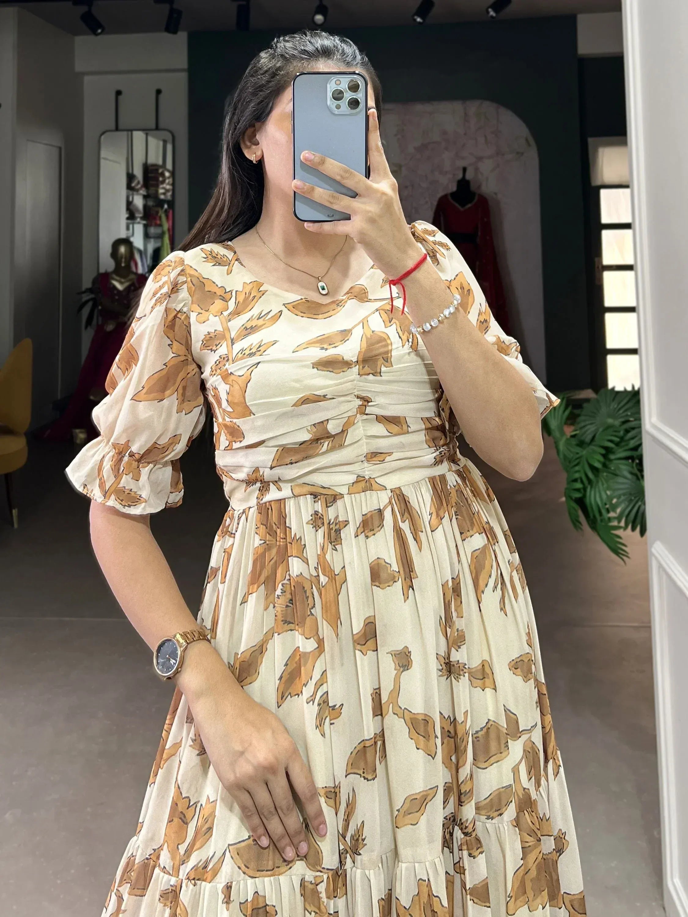 Woman wearing cream and brown floral long ethnic gown with puff sleeves, taking a mirror selfie