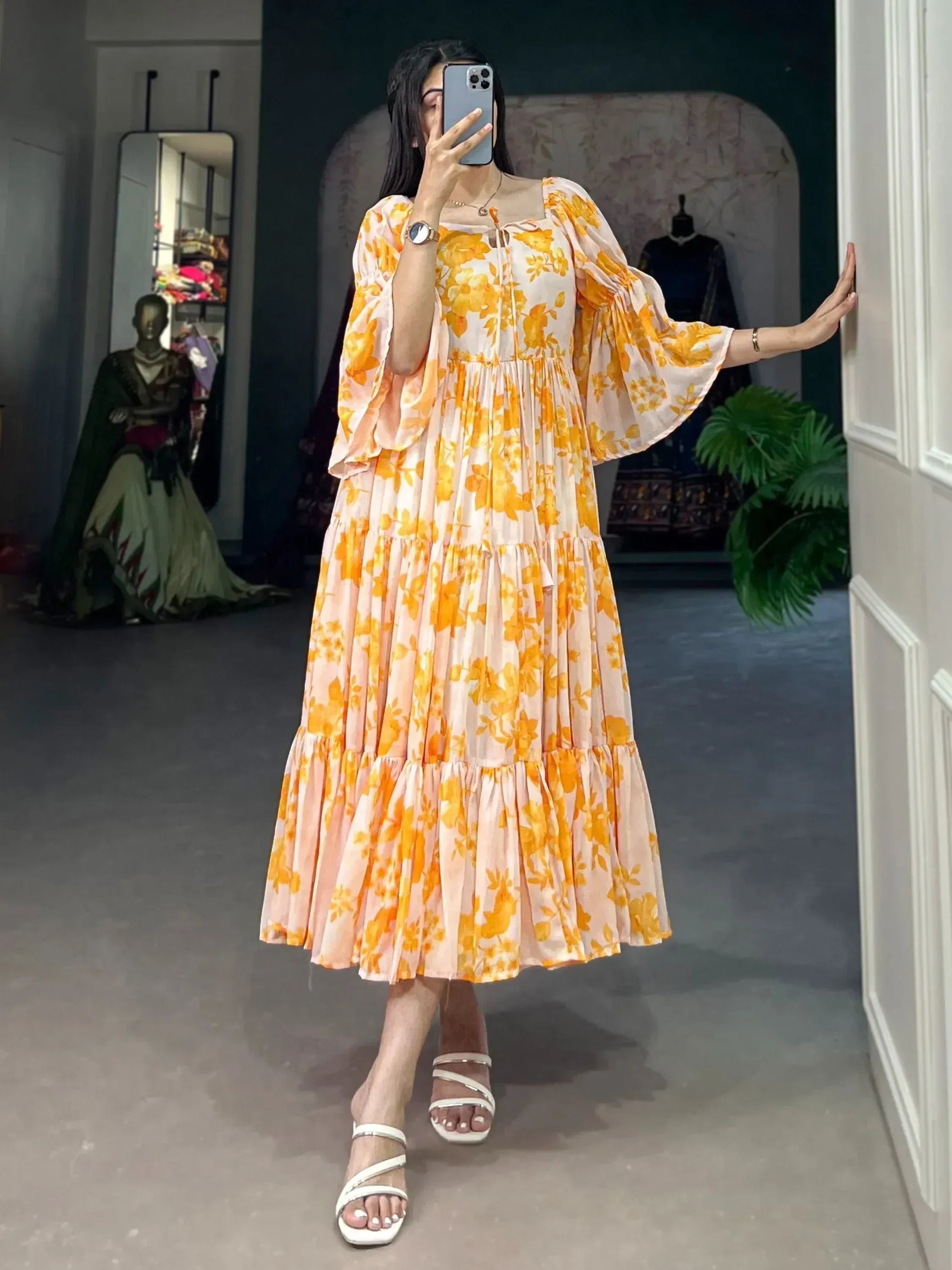 Woman wearing flowy yellow floral printed ethnic maxi dress with loose sleeves in a boutique