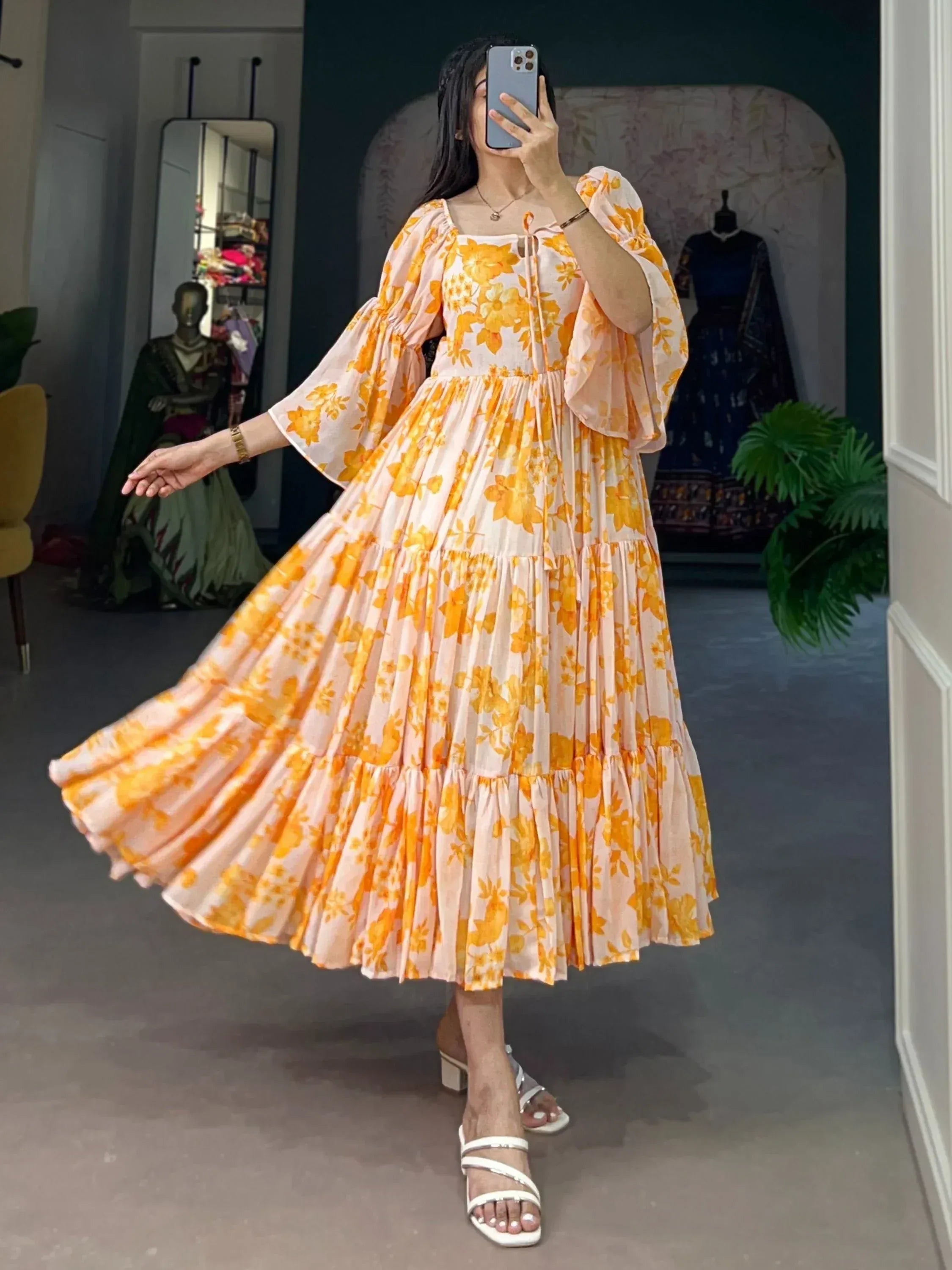 Woman in yellow floral long ethnic gown with flared sleeves and square neckline indoors