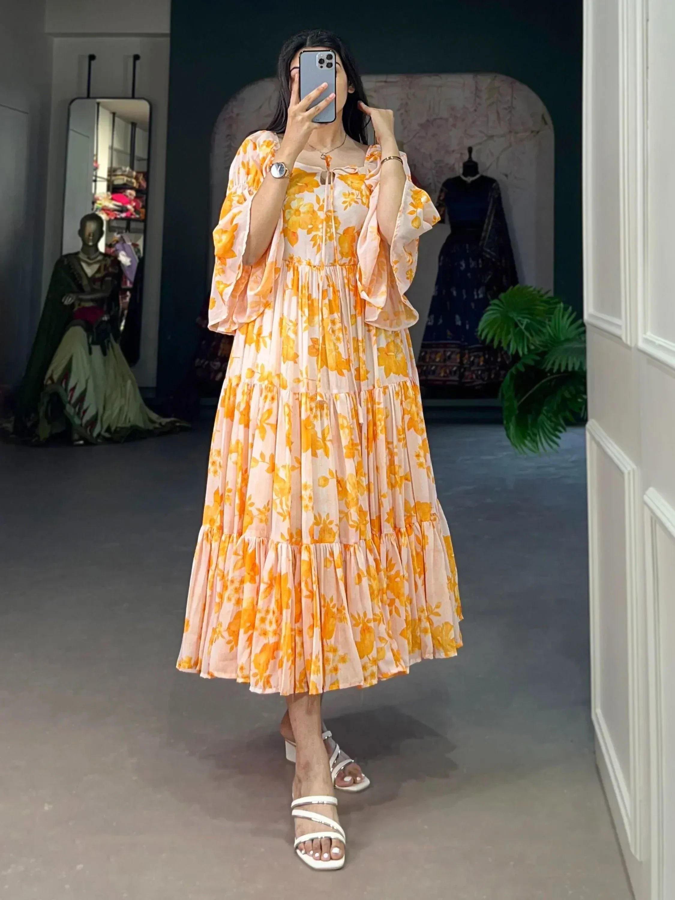 Woman wearing a yellow floral print ethnic gown with flared sleeves and tiered skirt