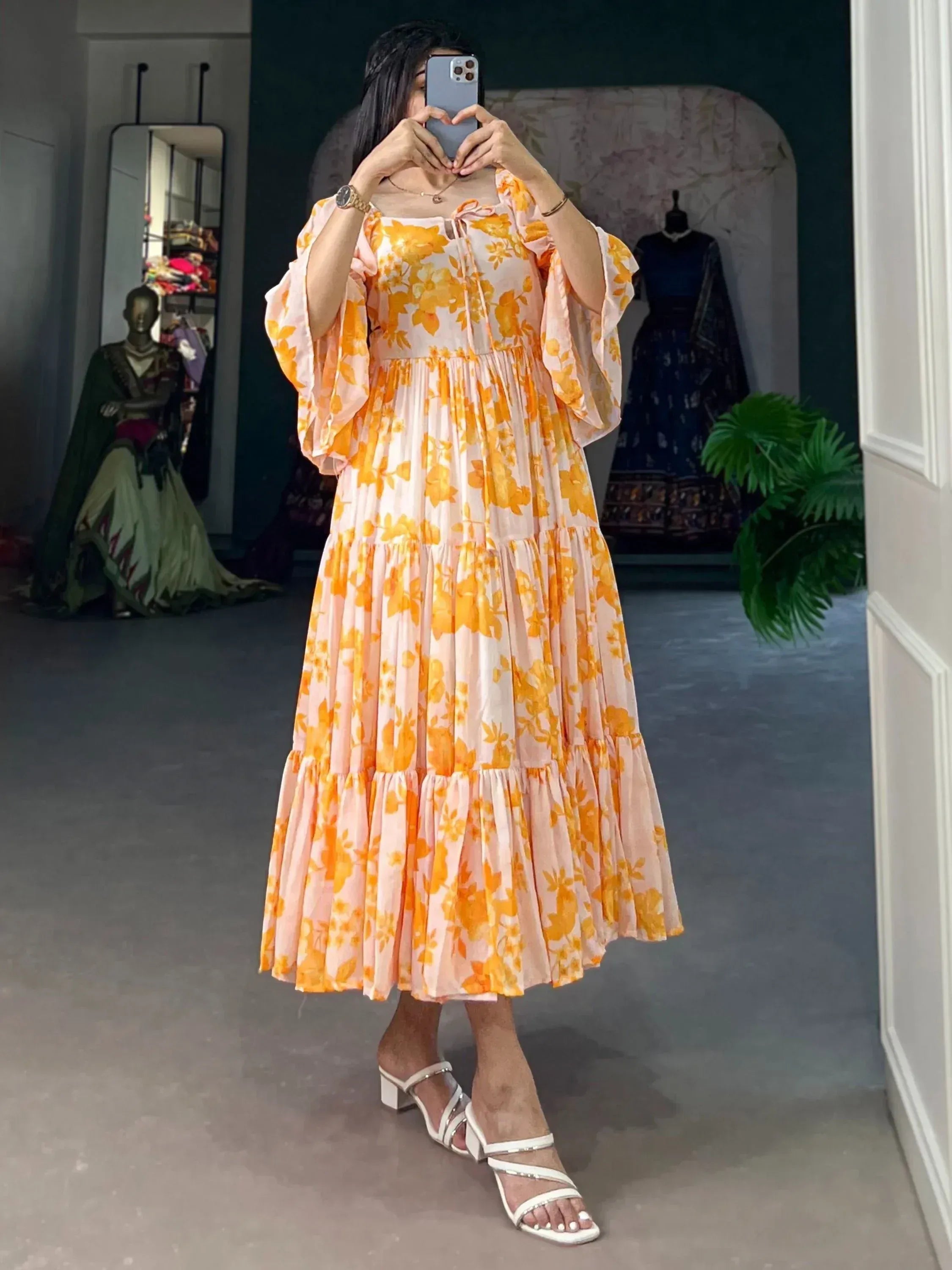 Woman wearing a yellow floral printed ethnic gown with flowy sleeves and white sandals