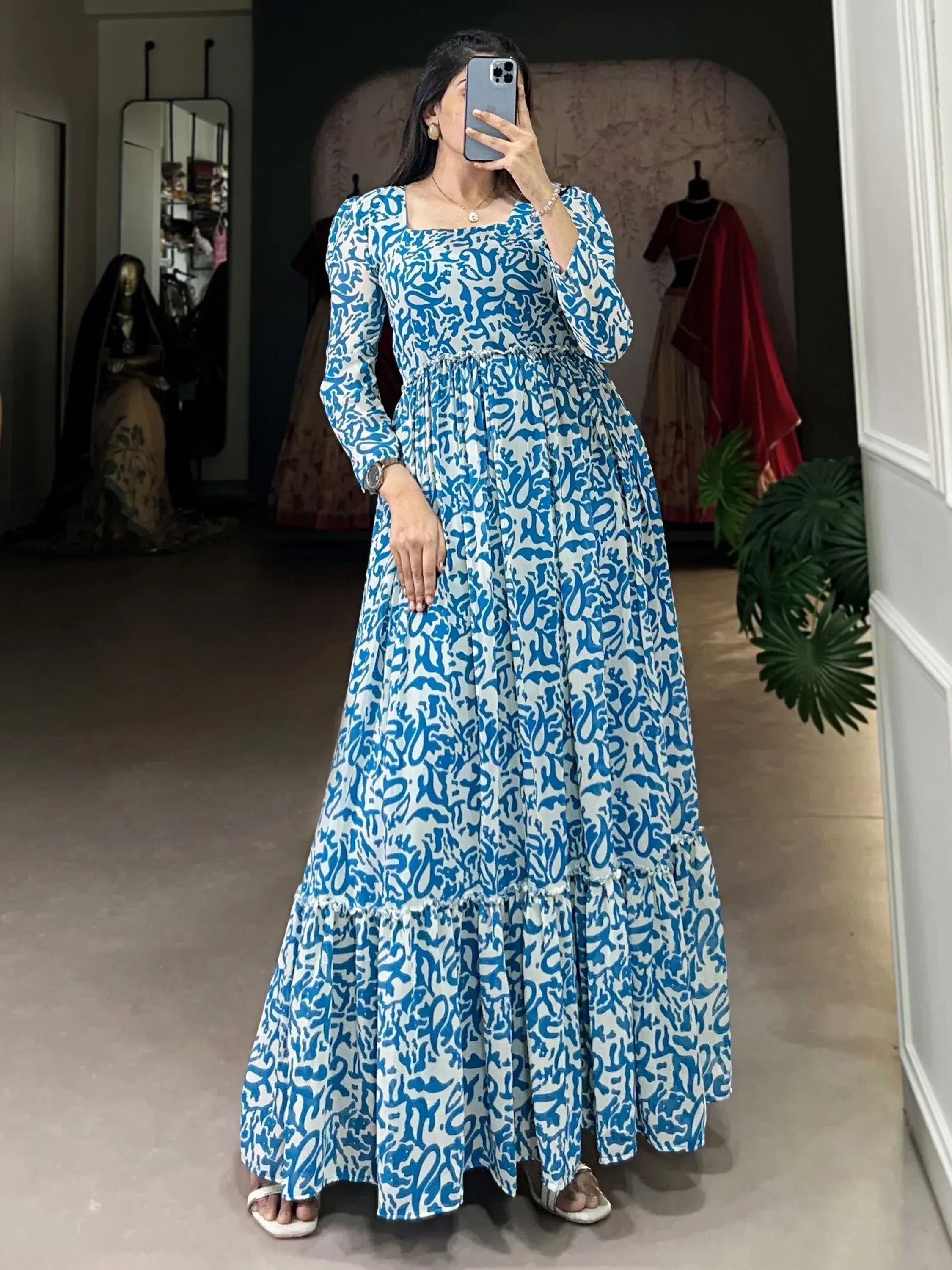 Blue and white printed ethnic gown with long sleeves and tiered skirt, perfect for festive occasions.