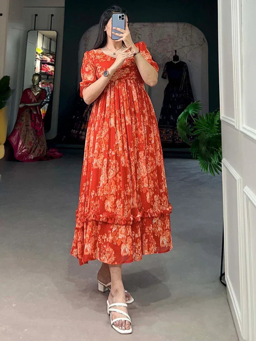 Orange floral print ethnic gown with ruffled hem, styled with white heels in boutique setting