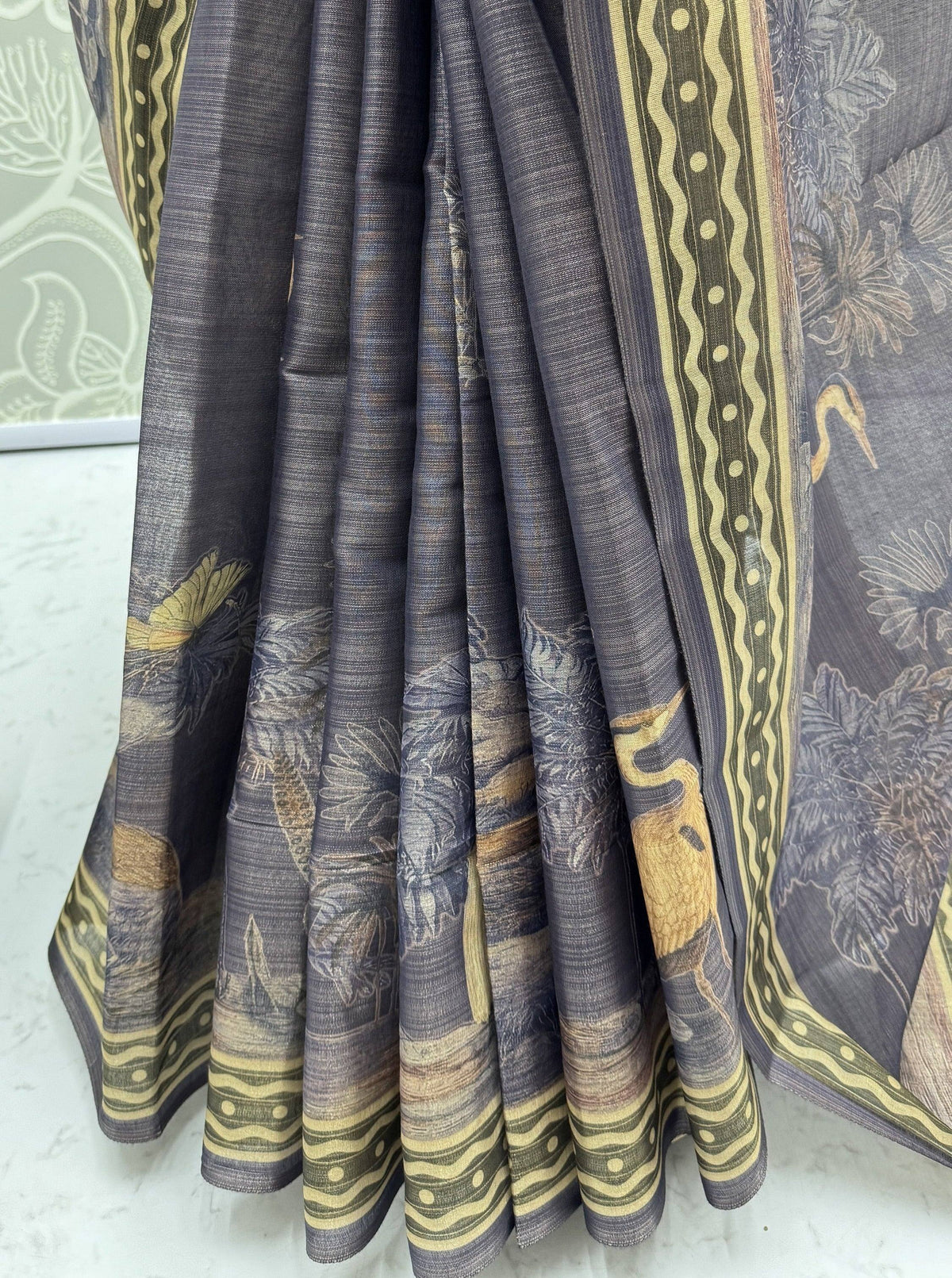 Close-up of a grey Indian ethnic saree with yellow bird and floral prints and a patterned border.