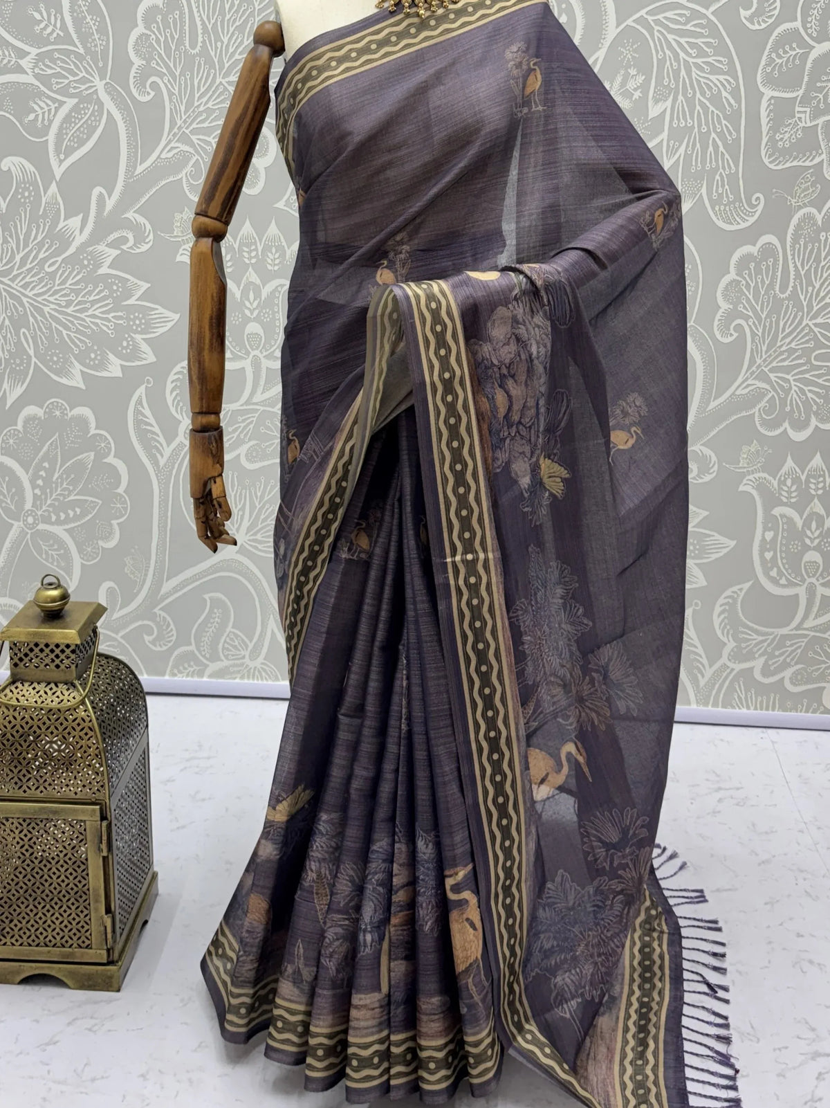 Elegant charcoal grey designer saree with gold borders and bird motifs on a mannequin