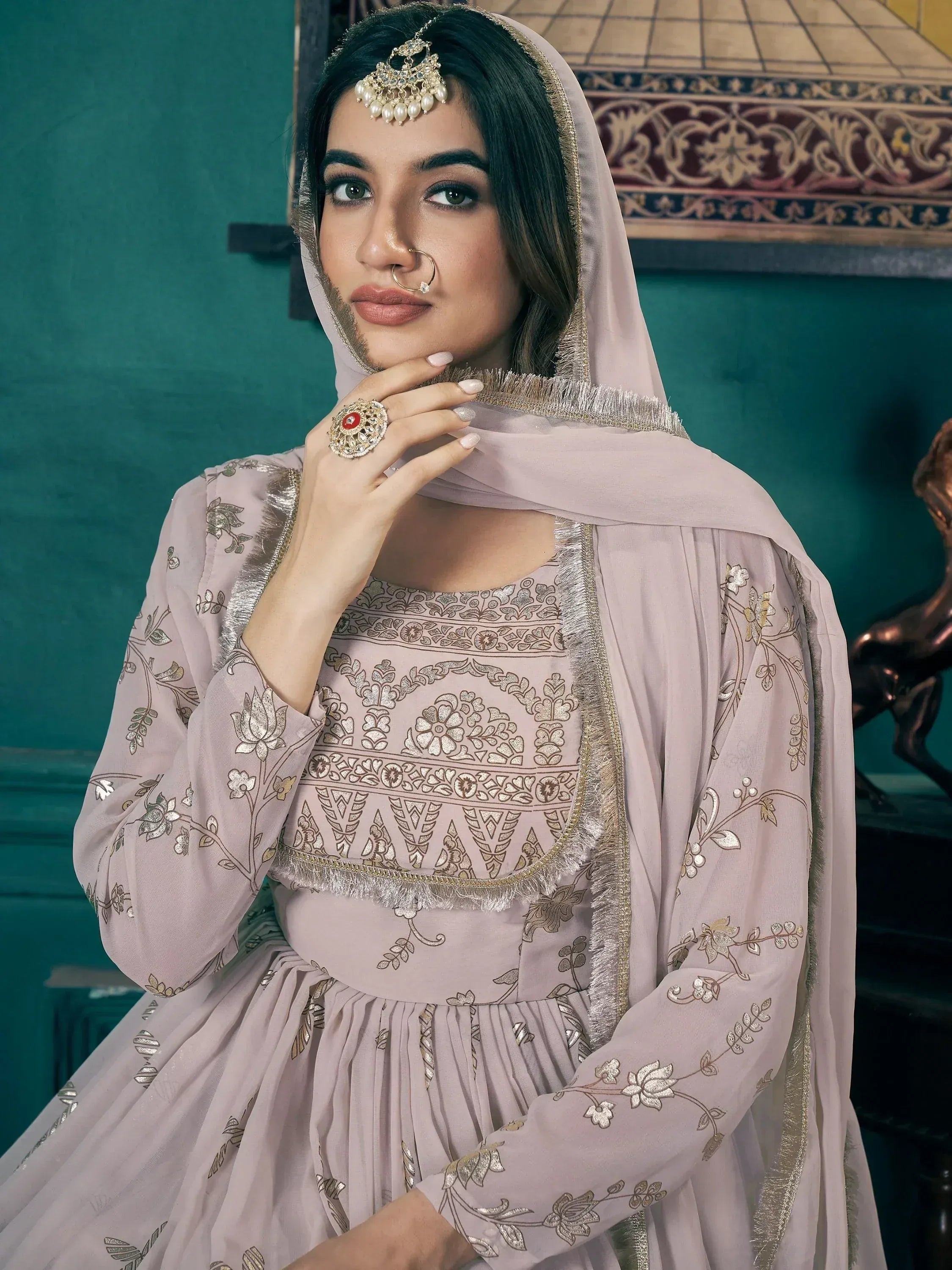 Elegant mauve ethnic gown with gold floral embroidery, paired with matching dupatta and traditional jewelry.
