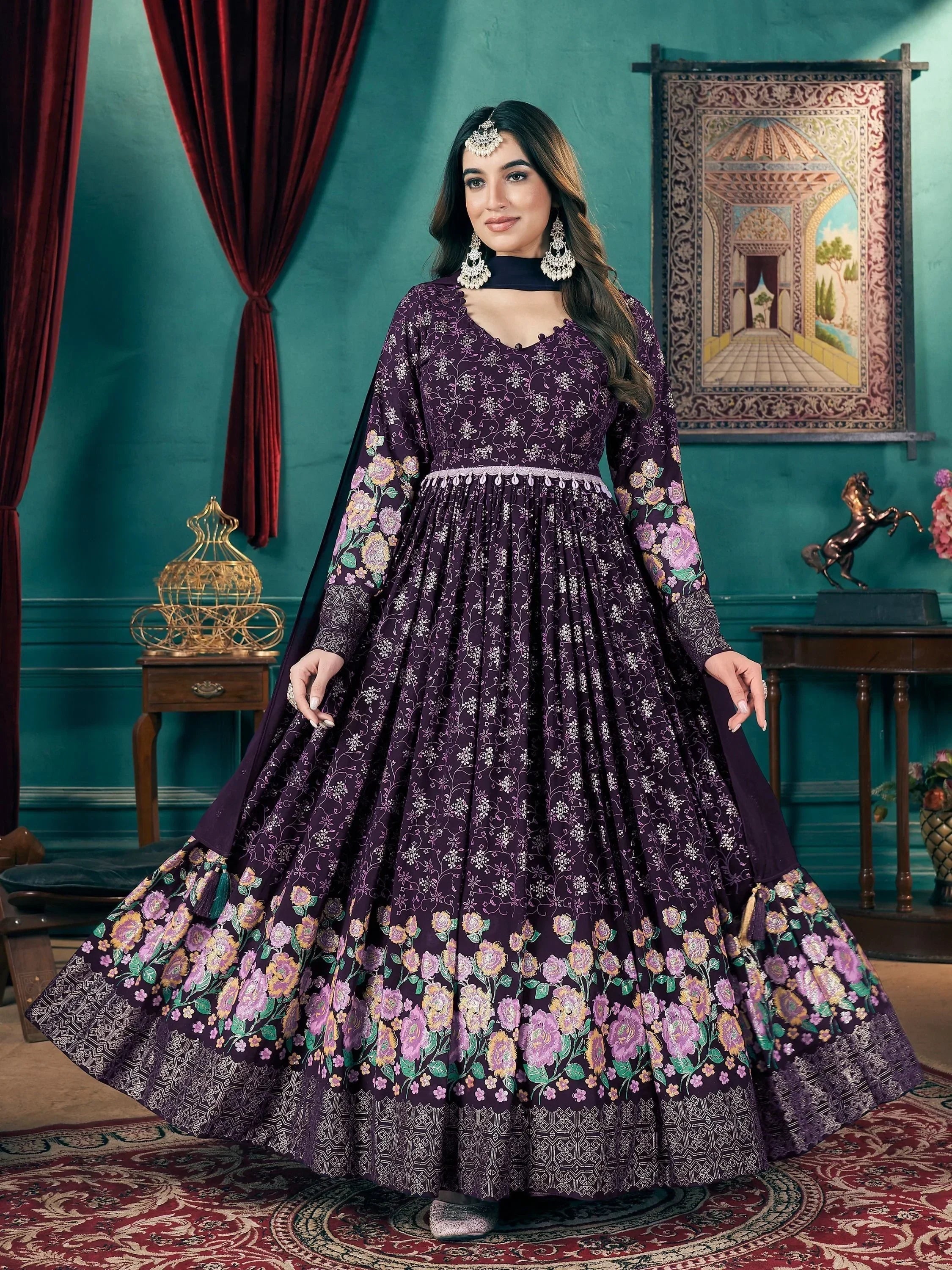 Woman wearing a purple embroidered ethnic gown with floral patterns in a traditional setting