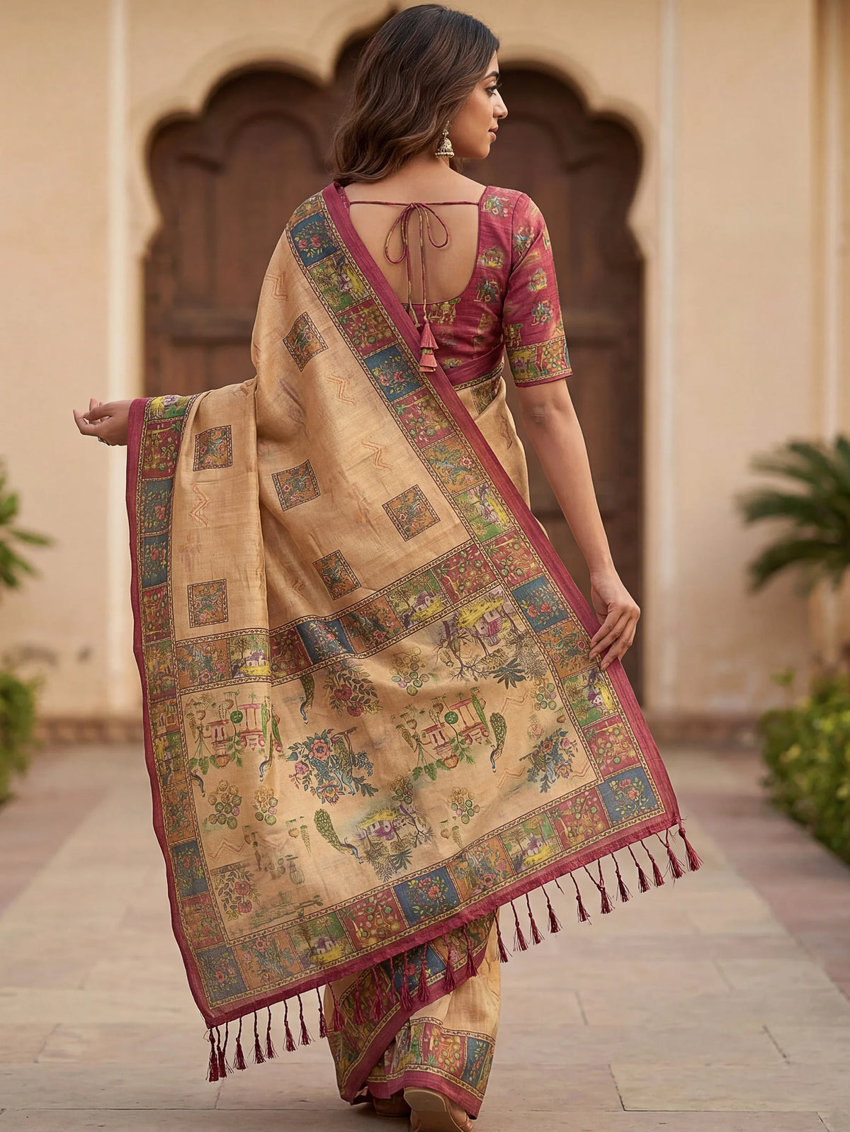 Woman in a beige printed silk saree with a magenta blouse and decorative border