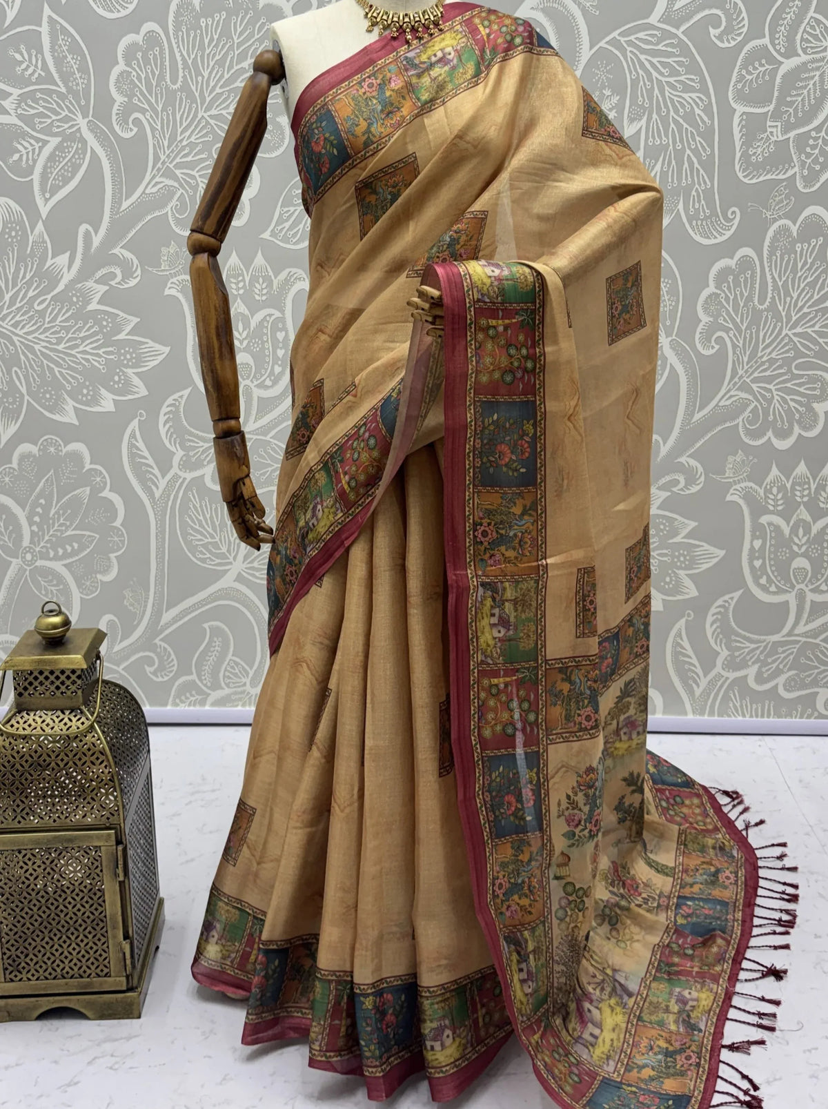 Beige designer saree with multicolor digital prints and a red border on a mannequin