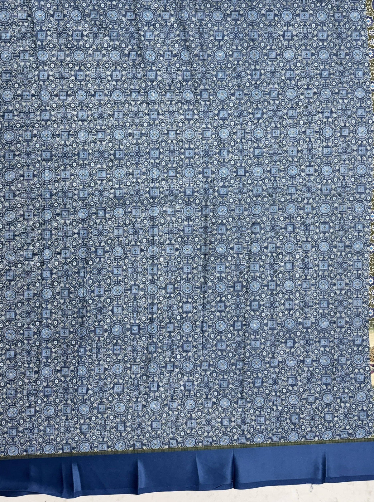Blue ethnic print saree fabric with a repeating circular geometric pattern and a solid blue border.