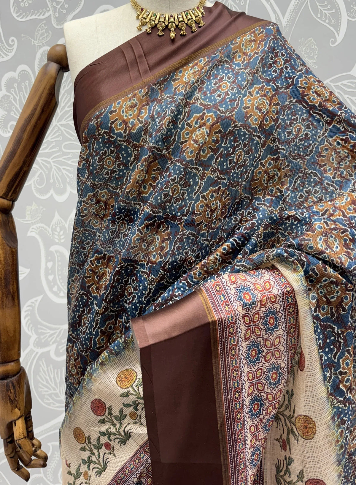 Brown and blue printed silk saree with traditional motifs on a mannequin