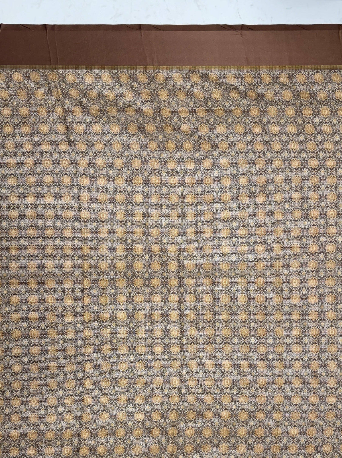 Detailed view of a brown and gold patterned ethnic saree fabric with a solid brown border