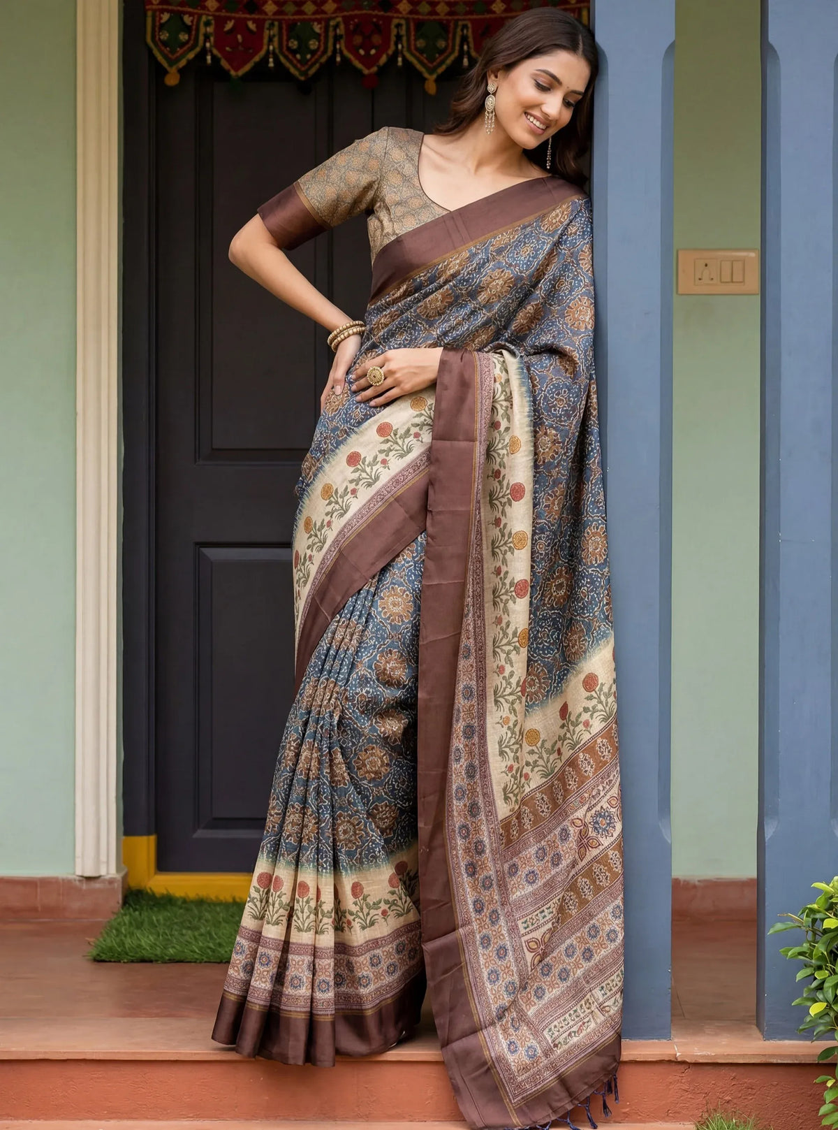Woman wearing a blue printed designer saree with a brown border and matching blouse