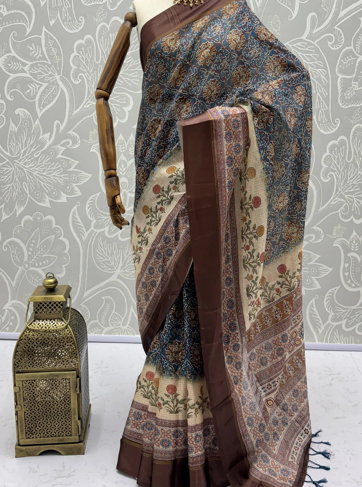 Designer printed saree with floral motifs and a brown border on a mannequin