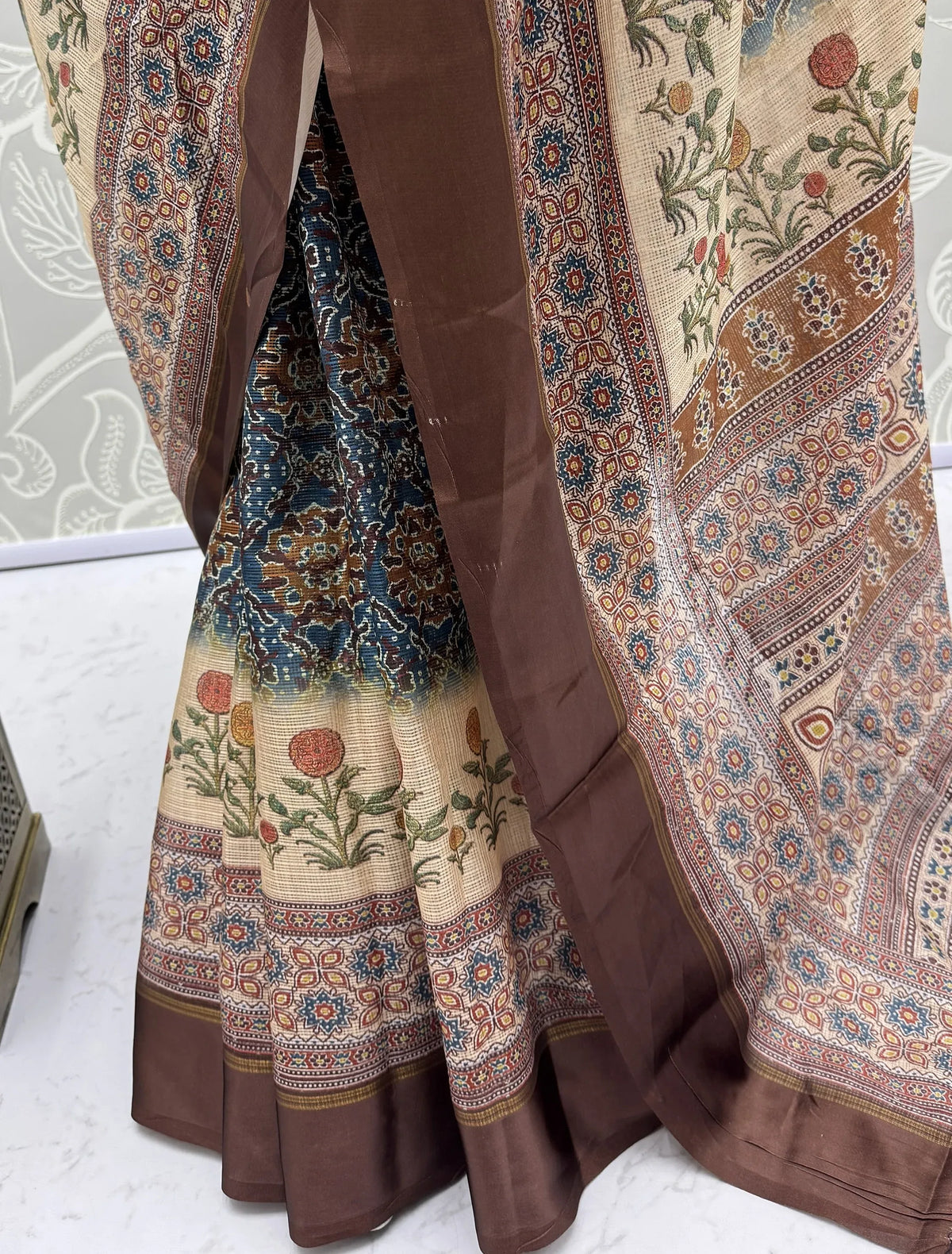 Close-up of a designer ethnic saree with floral prints and a brown satin border