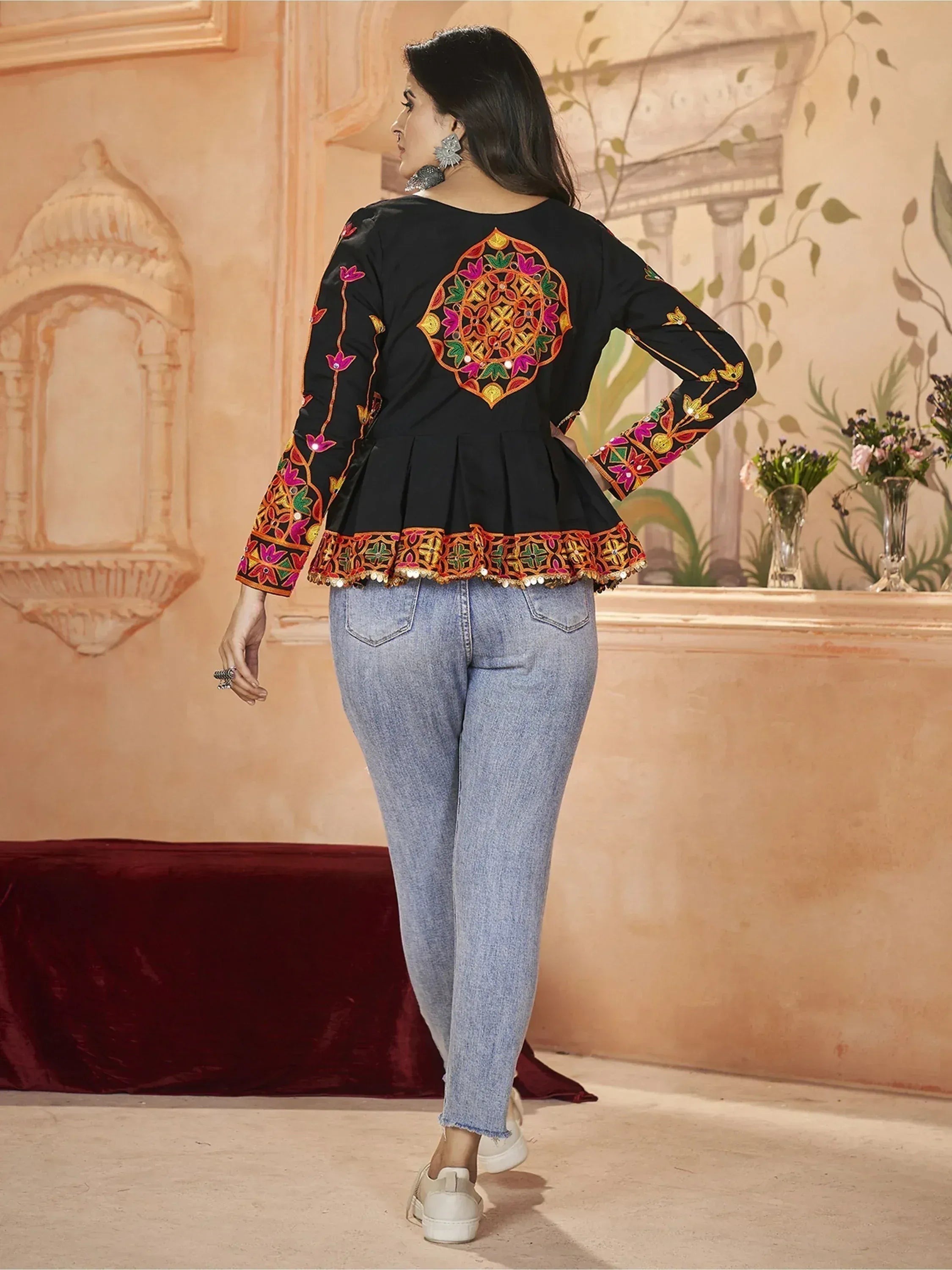 Black embroidered peplum top with colorful floral motifs, paired with jeans, showcasing ethnic wear design