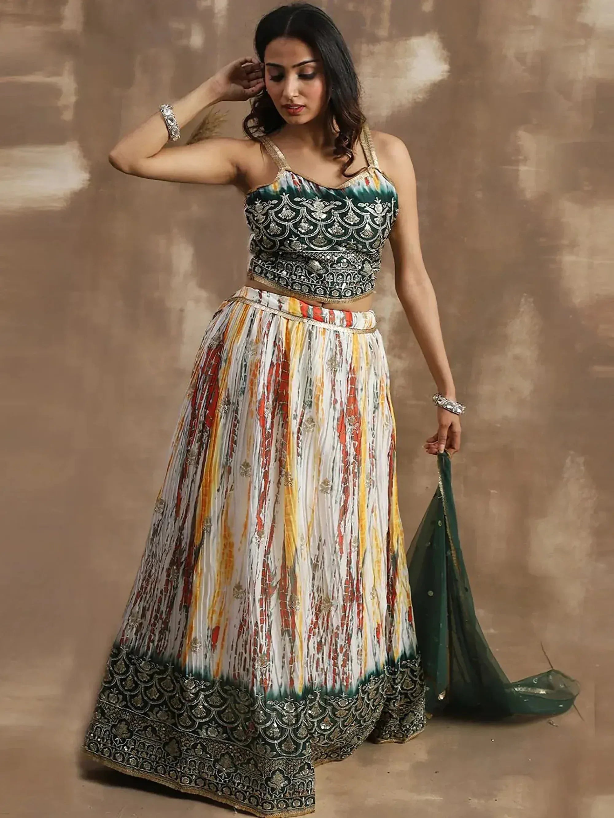 Woman in designer lehenga choli with embroidered green top, colorful pleated skirt, and matching dupatta