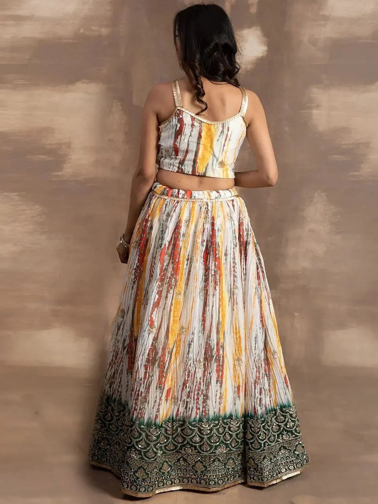 Back view of woman in colorful printed lehenga choli with embroidered green border, ethnic Indian wear