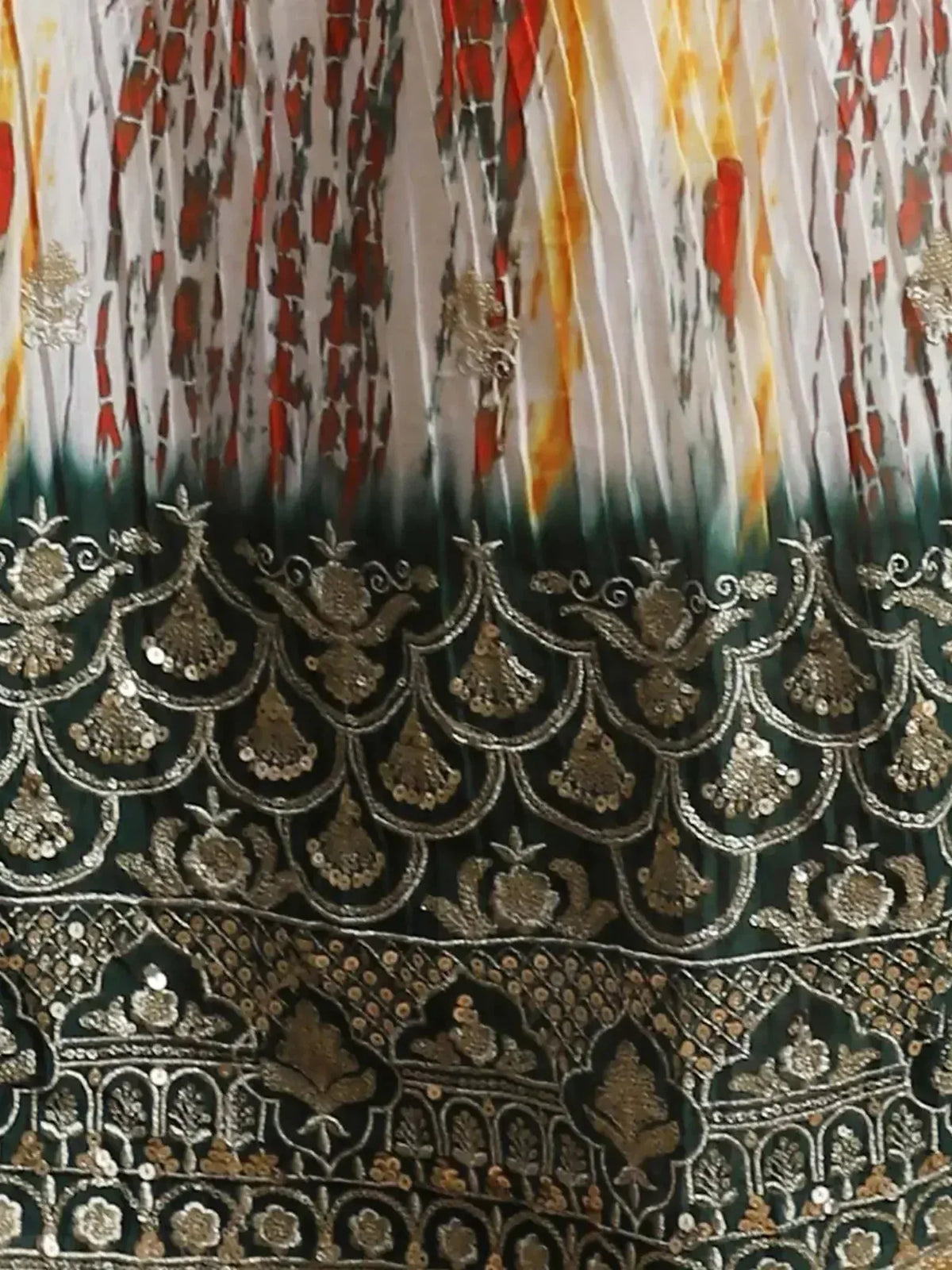 Designer lehenga with intricate gold embroidery, sequins, and tie-dye print in red, yellow, green, and white.