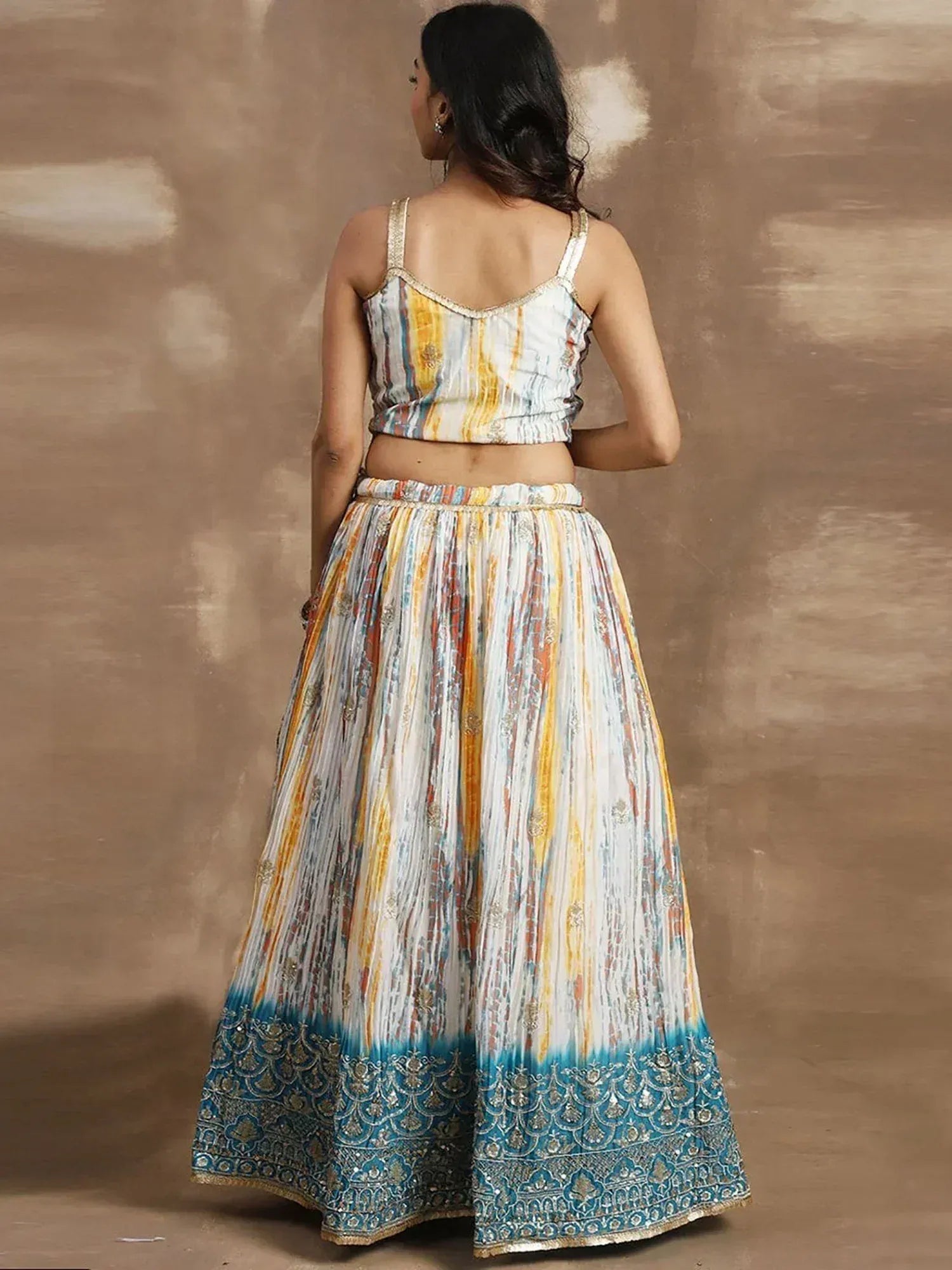 Back view of woman in colorful printed lehenga choli with blue embroidered border, ethnic Indian wear