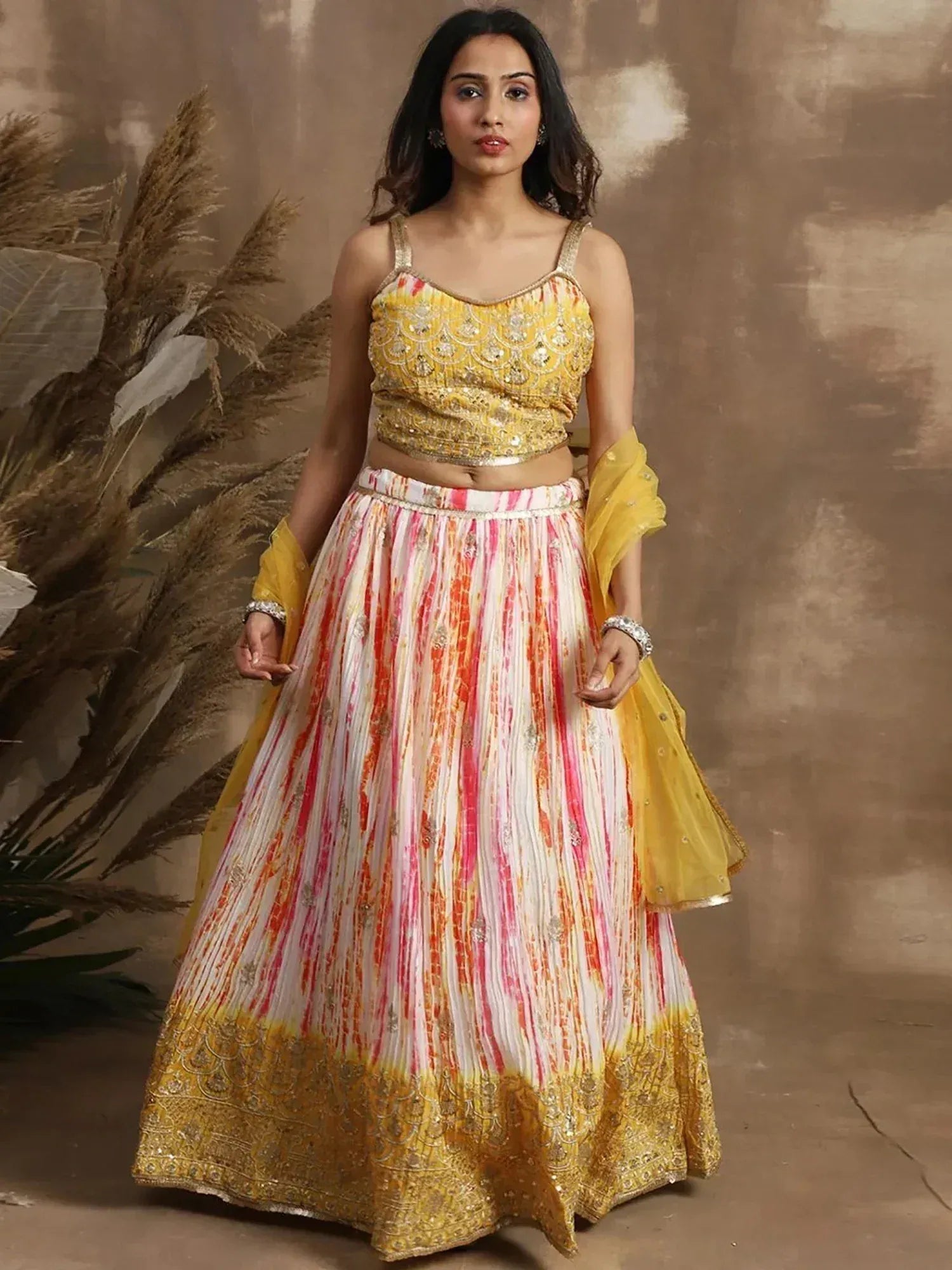 Yellow and pink tie-dye lehenga choli with gold embroidery, perfect for Indian ethnic wear events