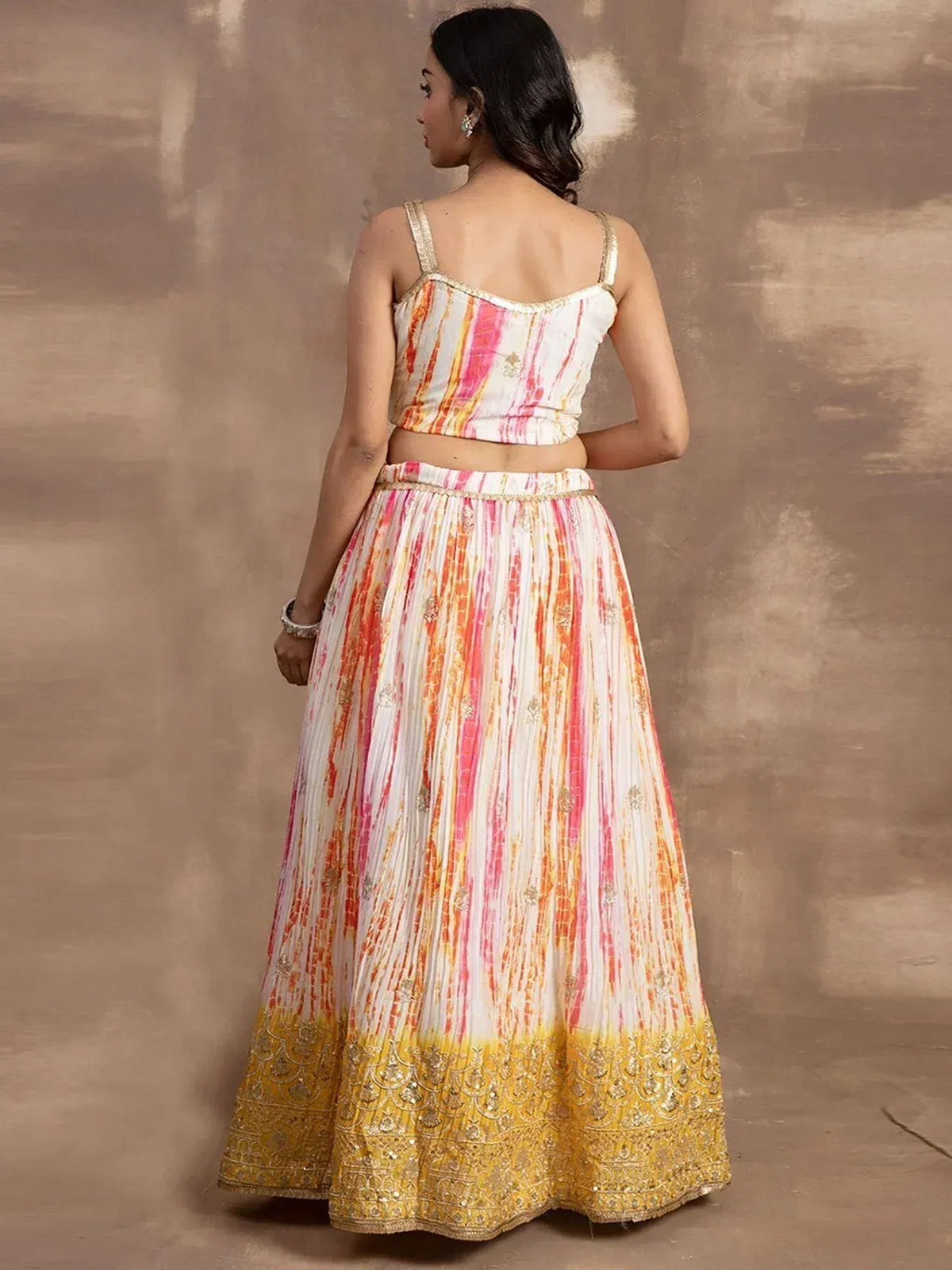 Woman in vibrant tie-dye lehenga choli with gold embroidery, Indian ethnic wear