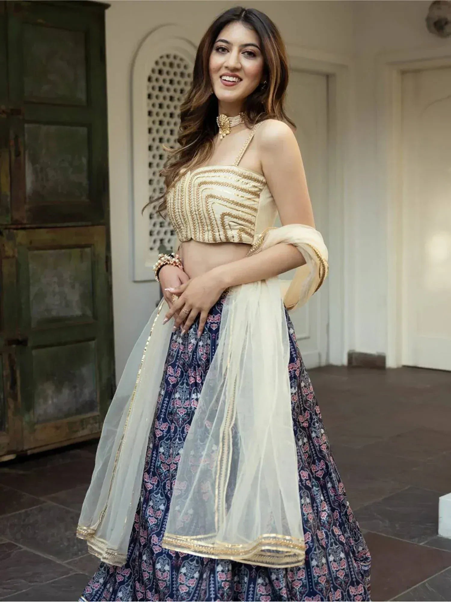 Woman in elegant Indian lehenga choli with gold embroidery and floral skirt, perfect for weddings or festivals