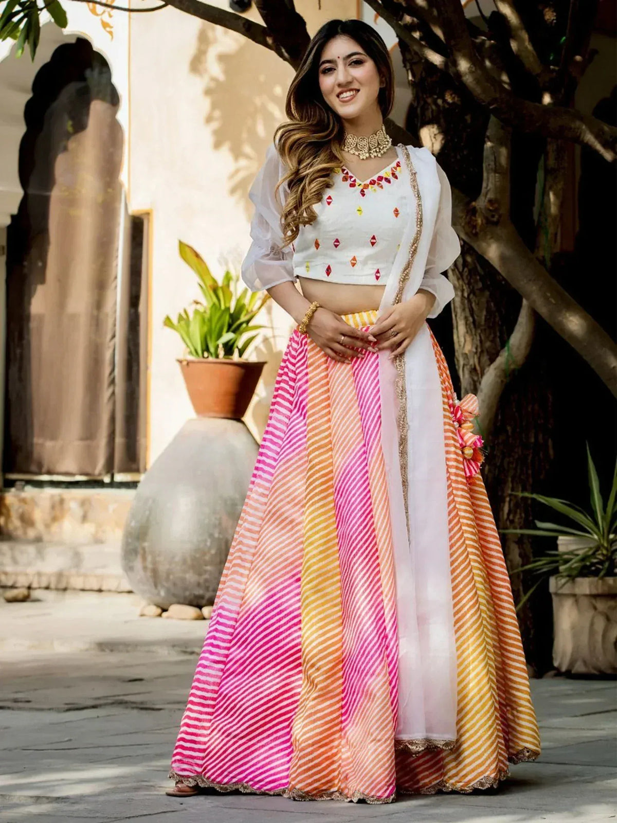 Woman in colorful striped lehenga choli with white crop top, perfect for Indian ethnic wear occasions
