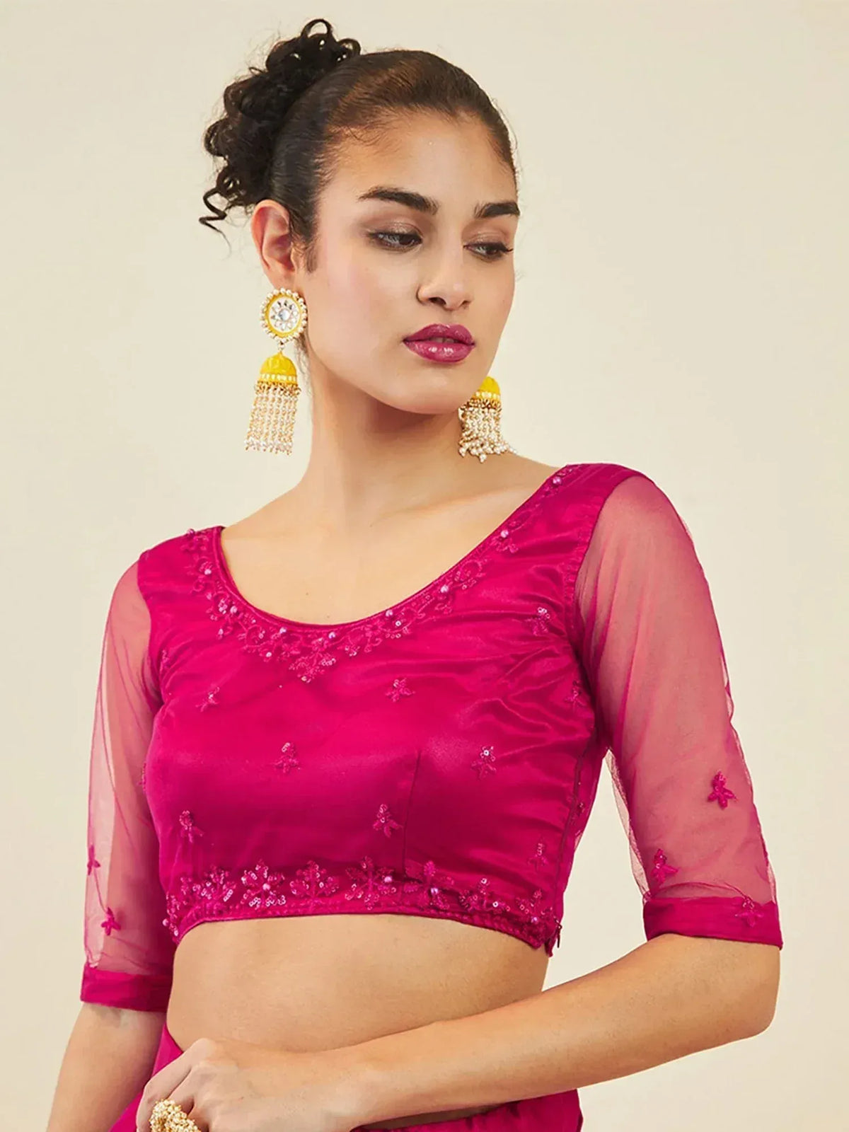 Fuchsia embroidered blouse with sheer sleeves and floral detailing, paired with traditional Indian jewelry.