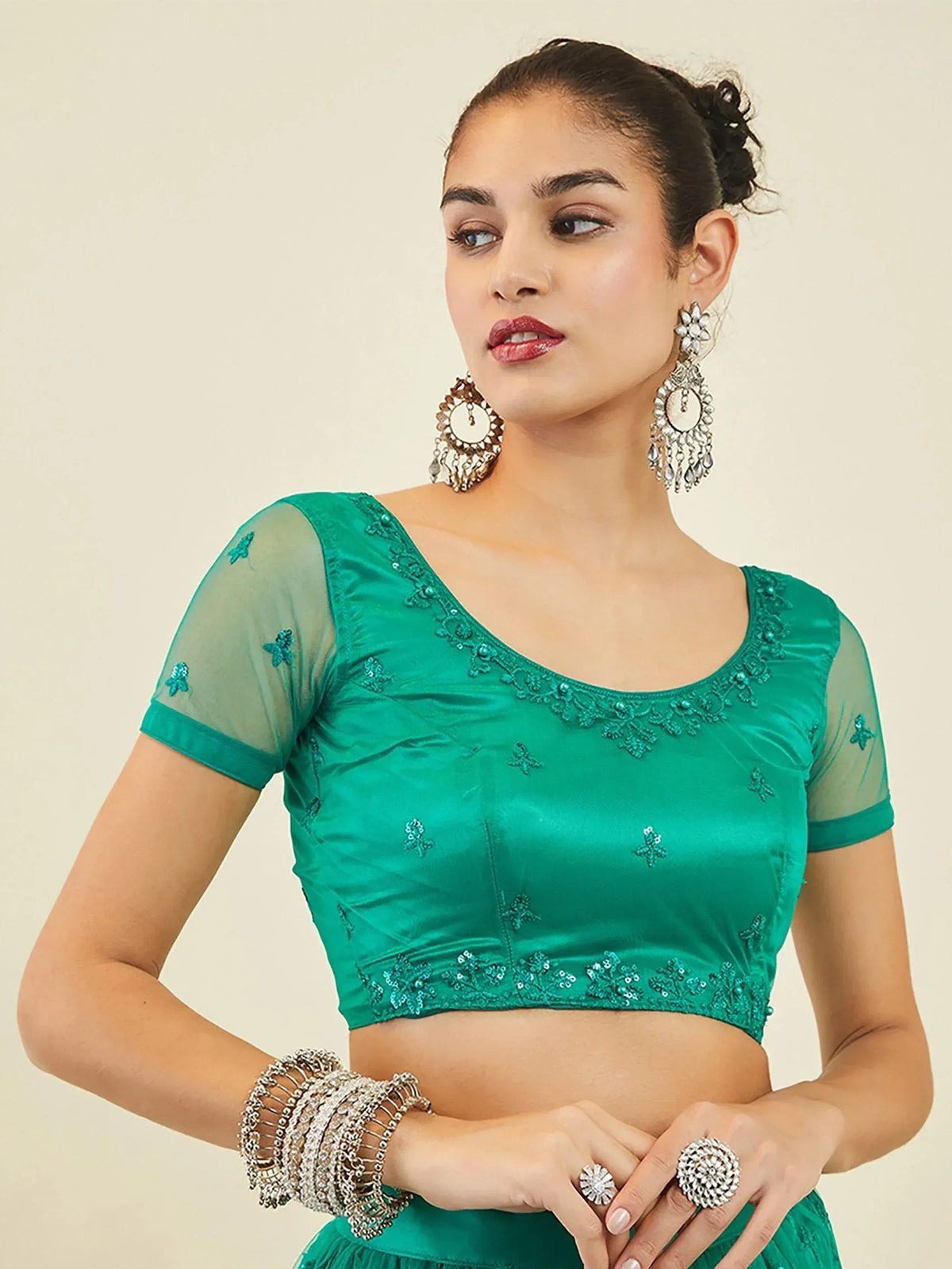 Emerald green embroidered blouse with sheer sleeves and traditional Indian jewelry