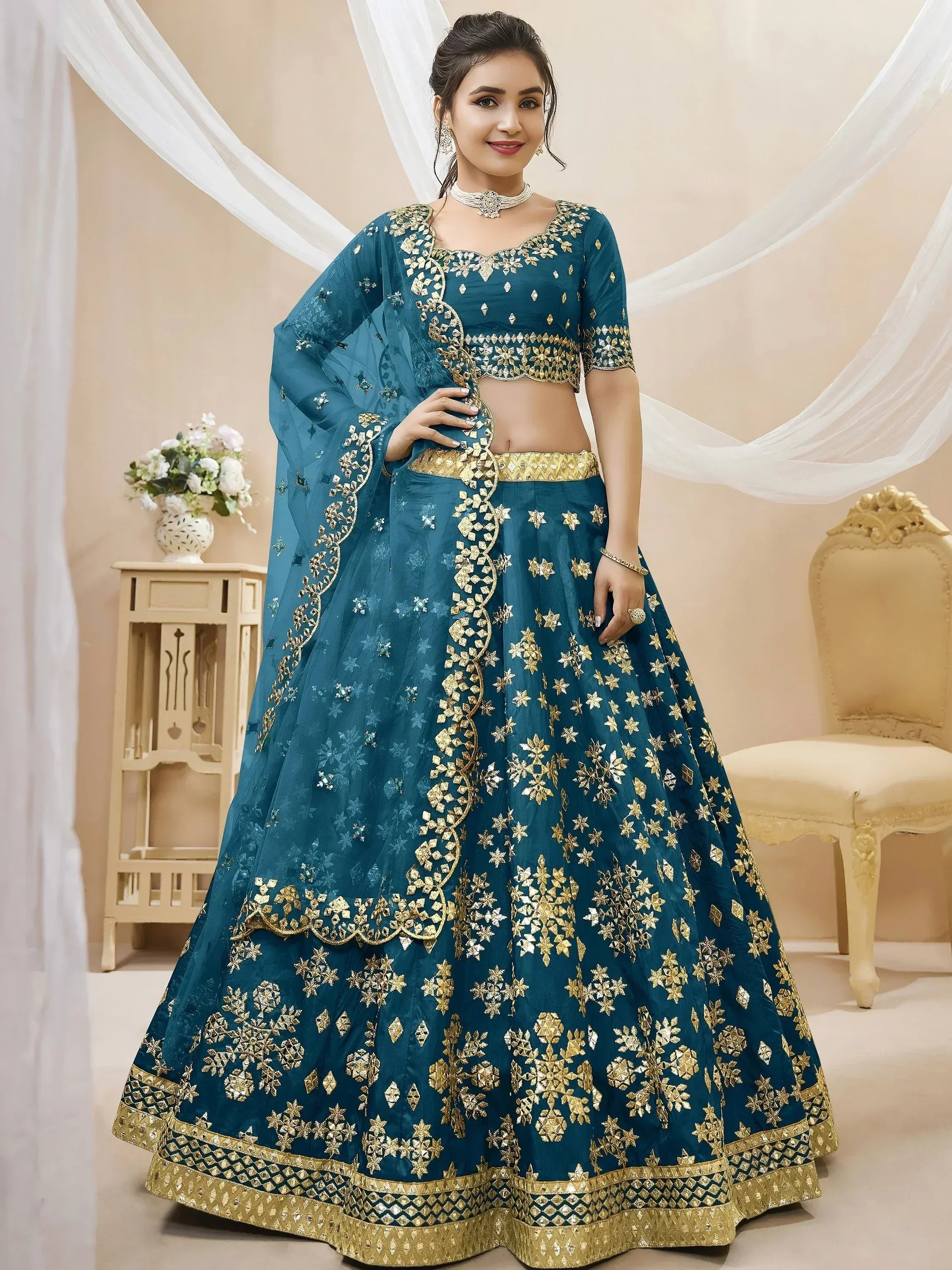 Teal blue designer lehenga choli with gold floral embroidery and sheer dupatta, perfect for weddings and festive occasions.