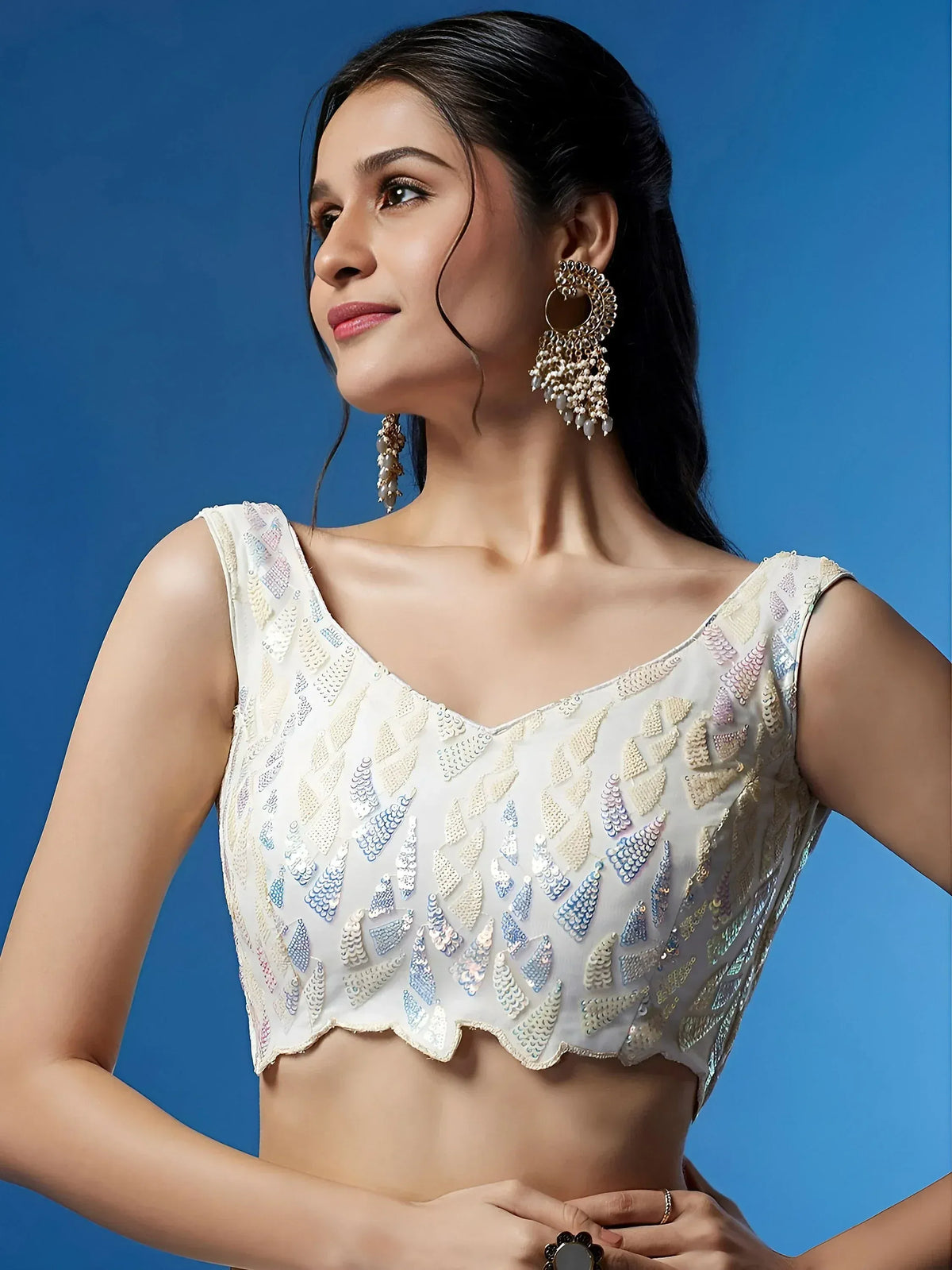 White embroidered blouse with sequin detailing, perfect for lehenga choli or saree, paired with statement earrings.