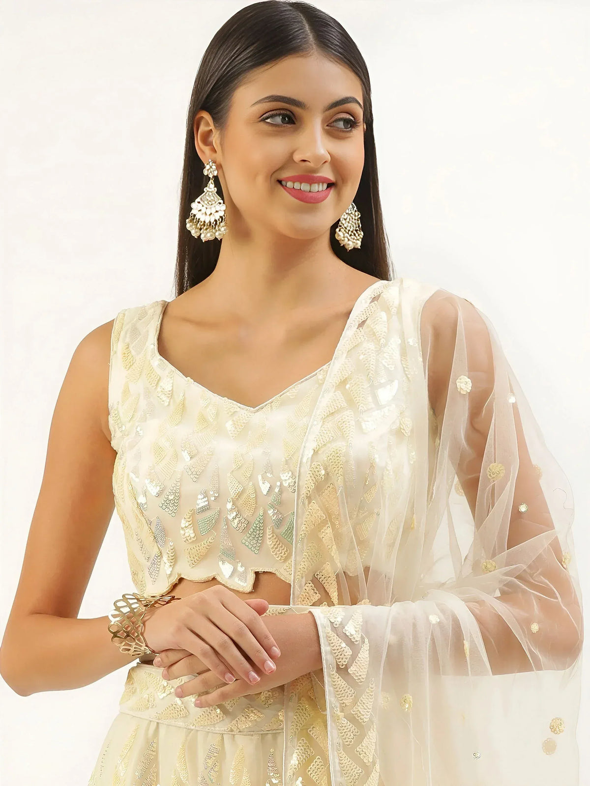 Elegant ivory lehenga choli with gold sequin embroidery and sheer dupatta, perfect for Indian ethnic wear occasions.