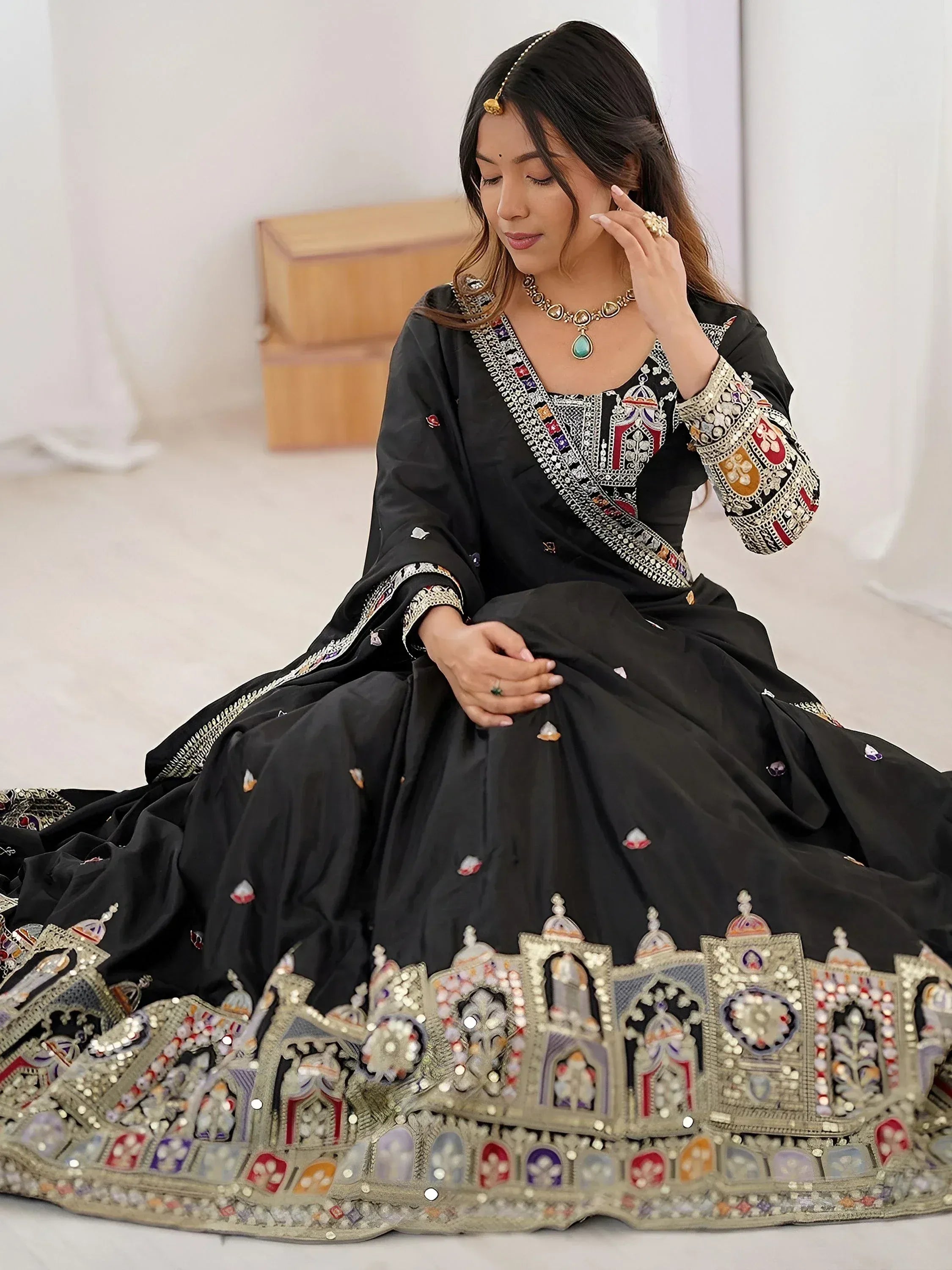 Black embroidered lehenga choli with intricate mirror work and traditional Indian jewelry
