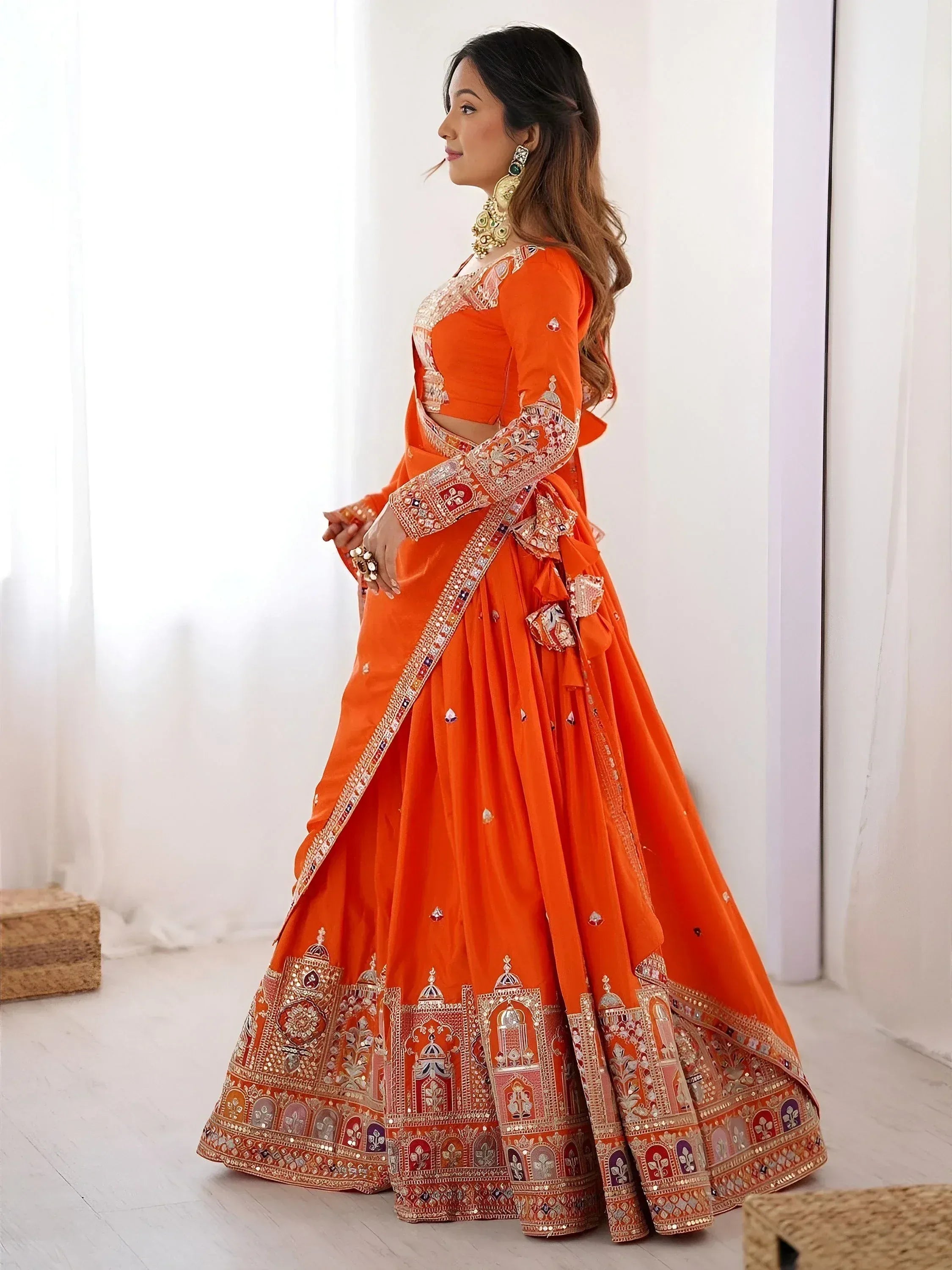 Orange designer lehenga choli with heavy embroidery and mirror work, perfect for Indian weddings and festive occasions