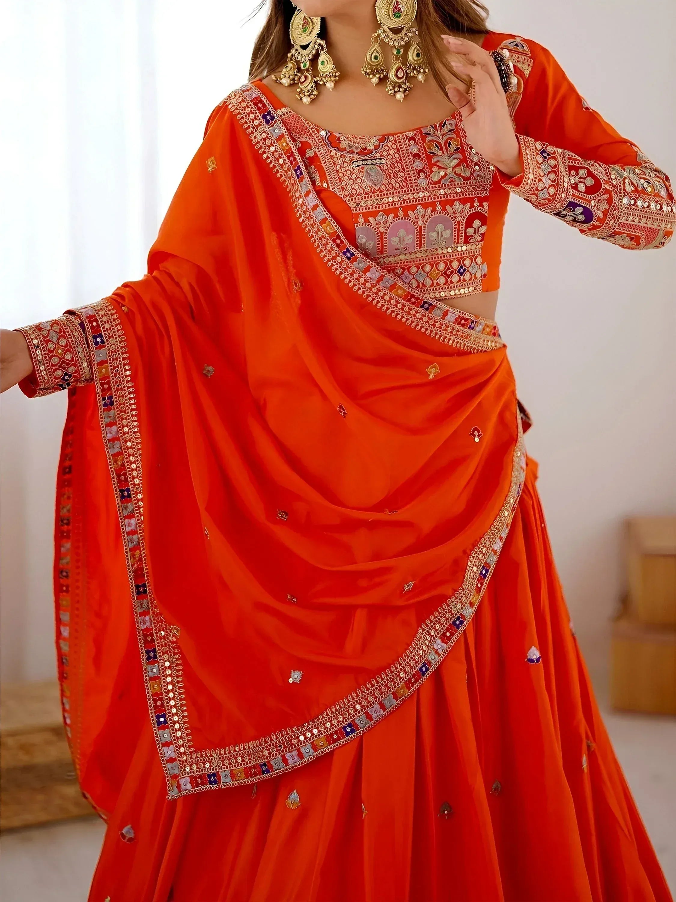Vibrant orange Indian lehenga choli with intricate embroidery and mirror work, perfect for festive occasions.