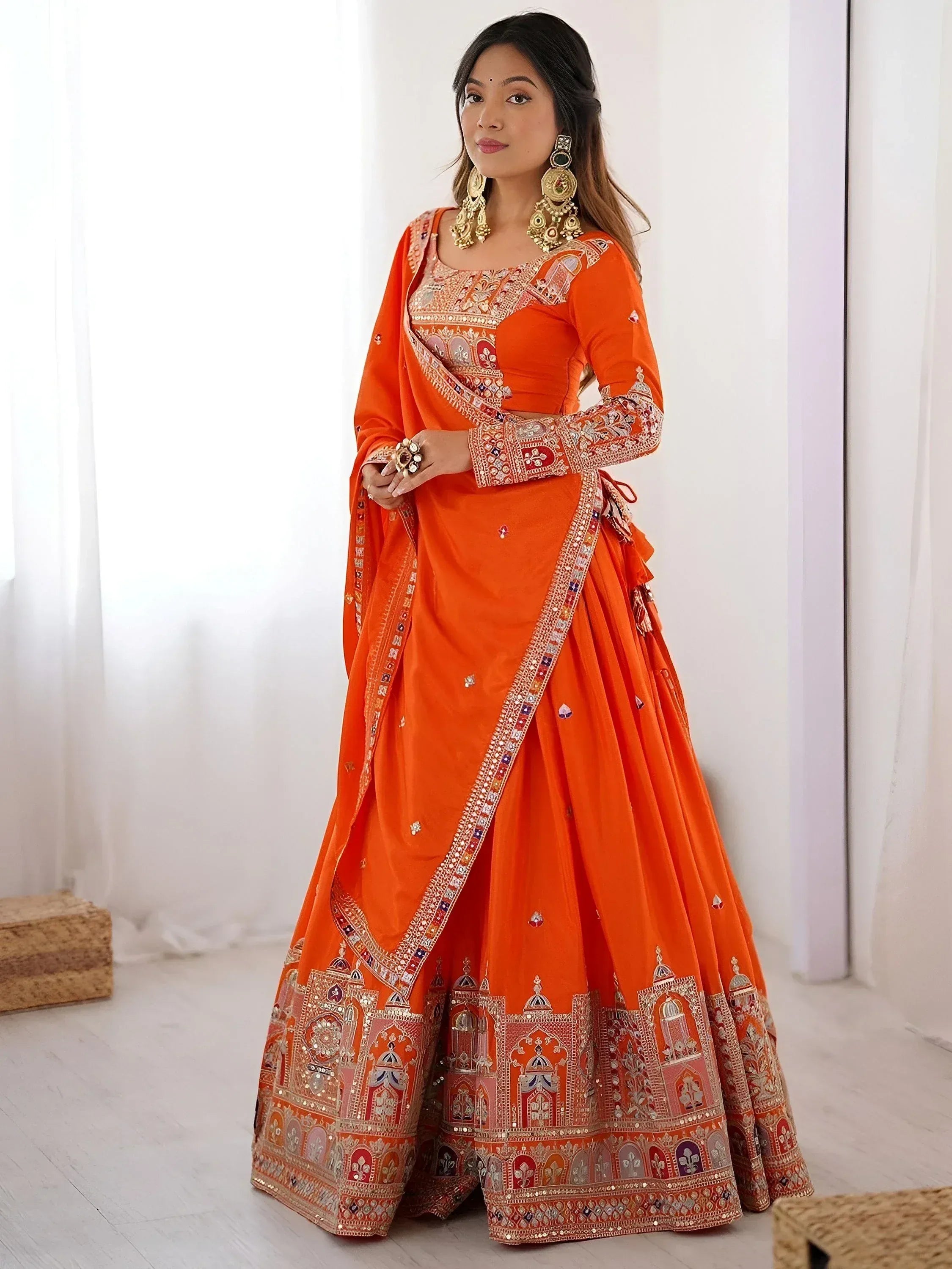 Orange designer lehenga choli with intricate embroidery and mirror work, perfect for Indian weddings and festive occasions.