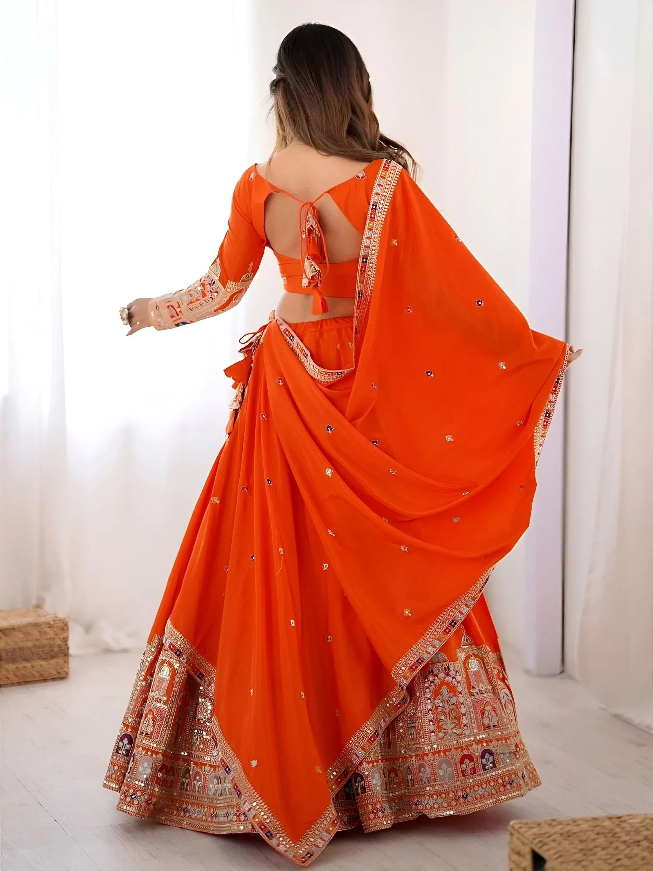 Orange designer lehenga choli with intricate embroidery and mirror work, perfect for Indian ethnic occasions