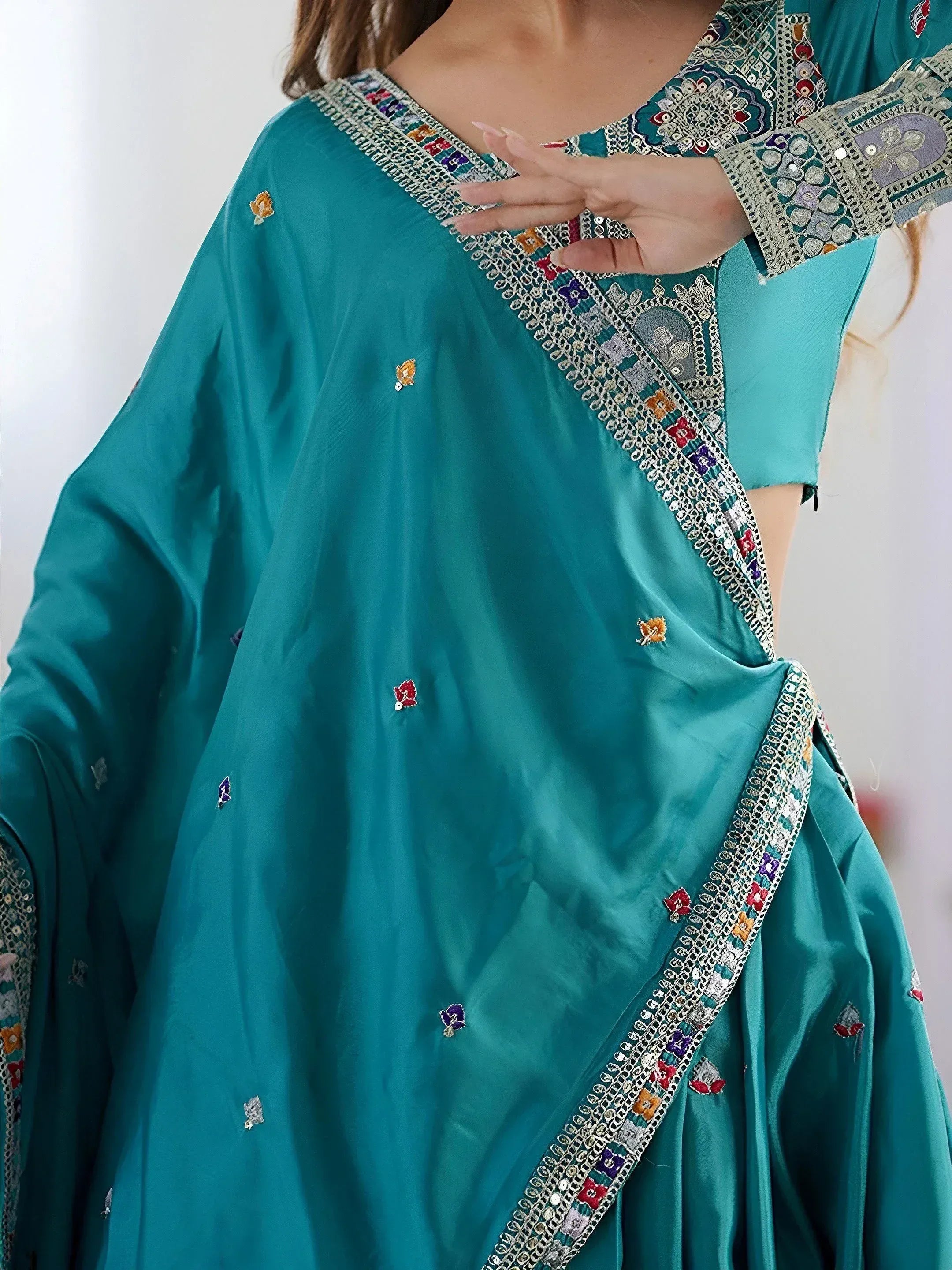 Teal ethnic gown with intricate floral embroidery and mirror work, perfect for festive occasions.
