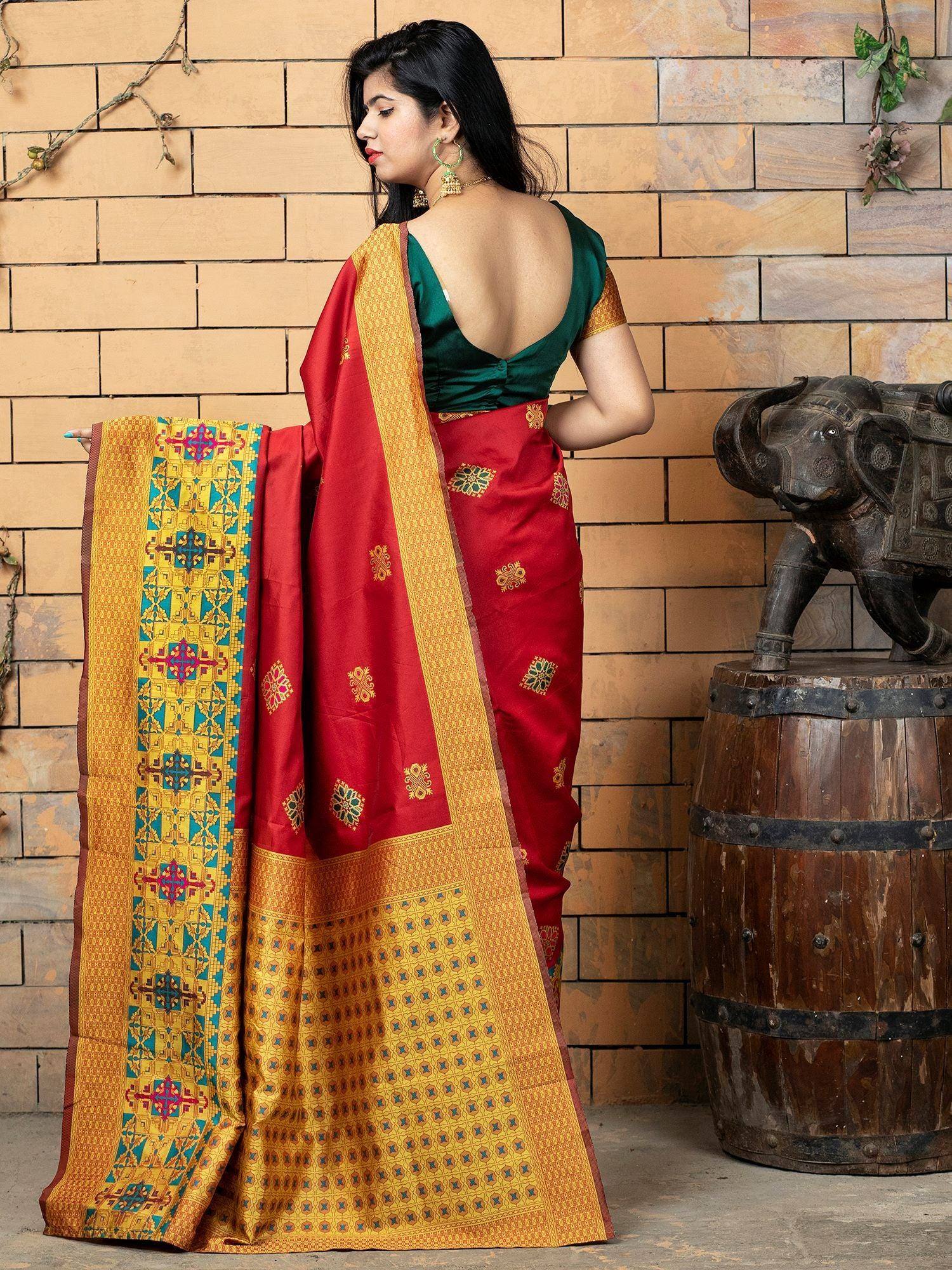 Red and gold ethnic saree with intricate geometric border, paired with green blouse, perfect for Indian occasions