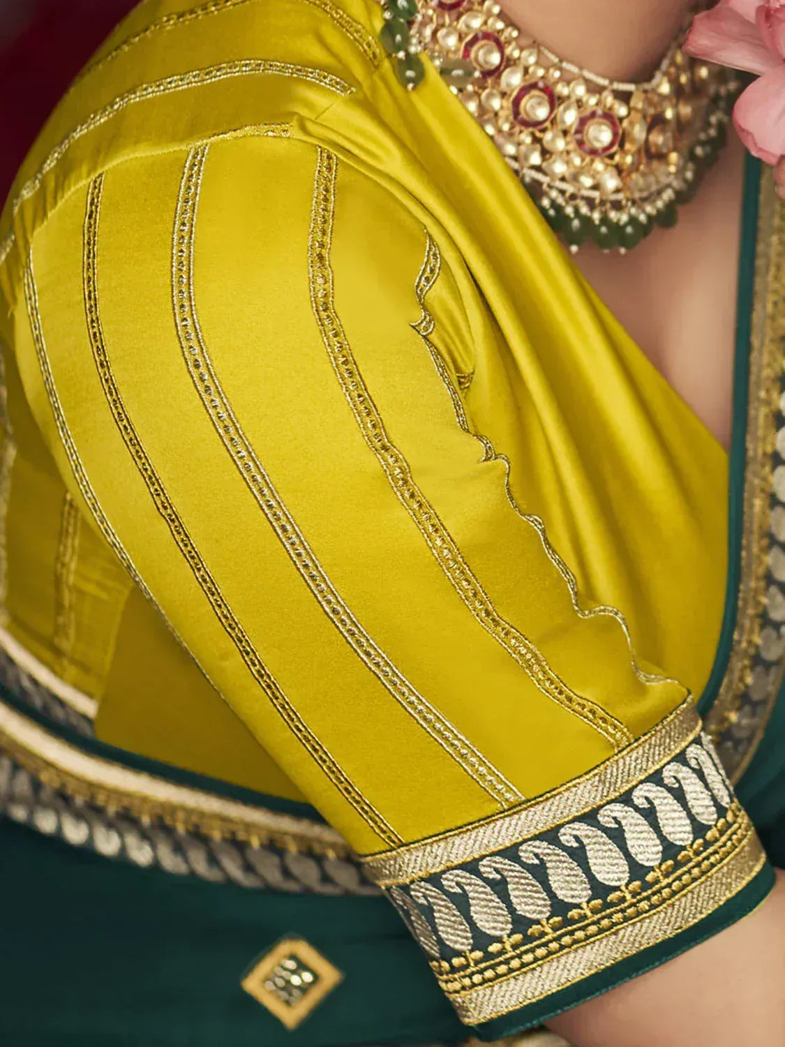 Yellow velvet blouse with gold embroidery, paired with green saree and traditional jewelry