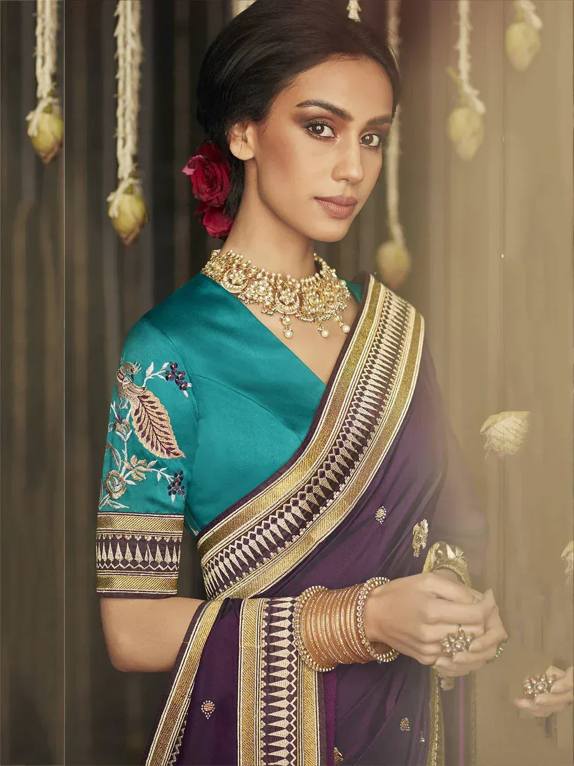Elegant purple and teal saree with gold border and peacock embroidery, paired with traditional jewelry