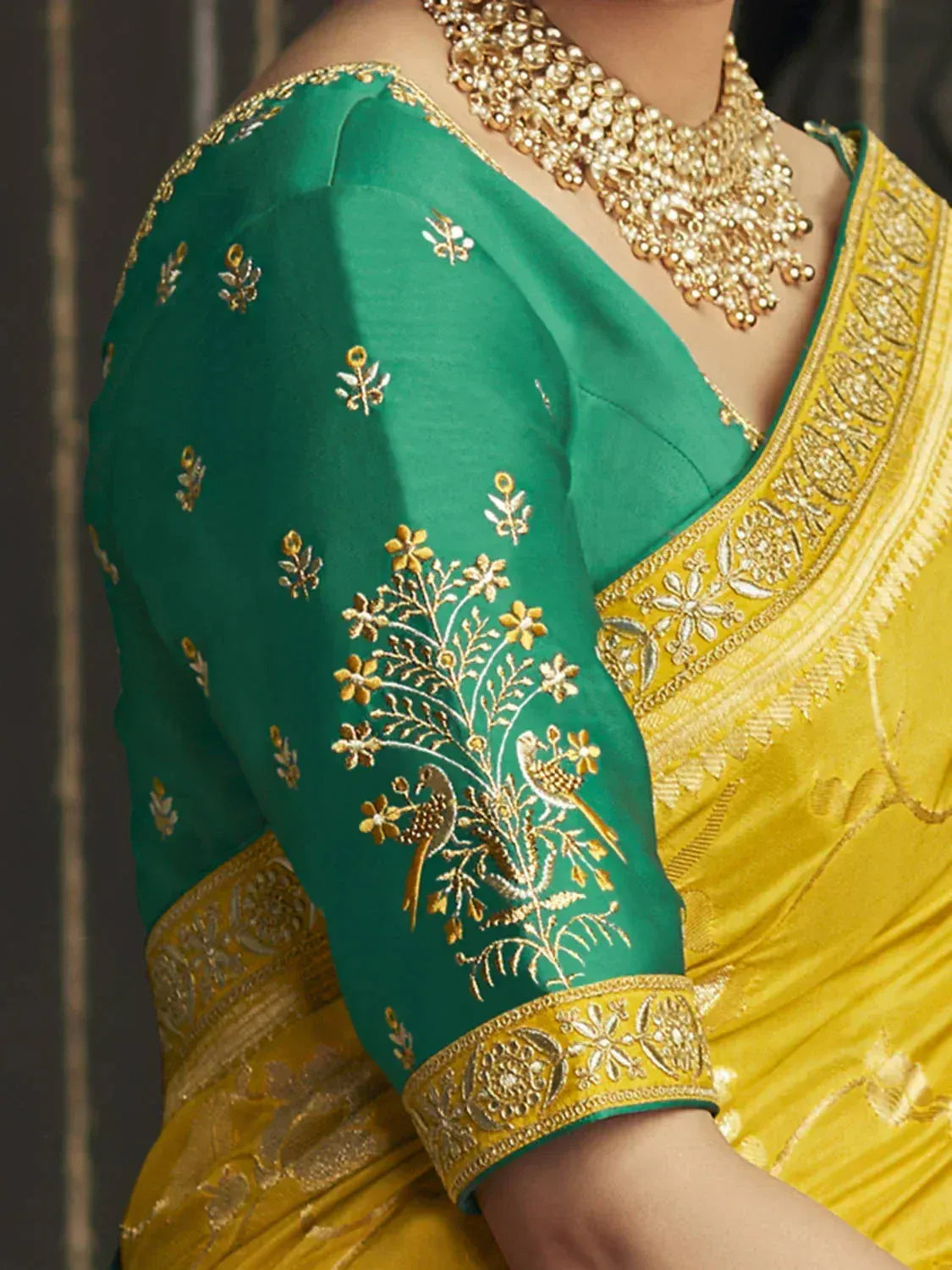 Green and yellow saree with gold embroidery, floral and bird motifs, paired with statement necklace