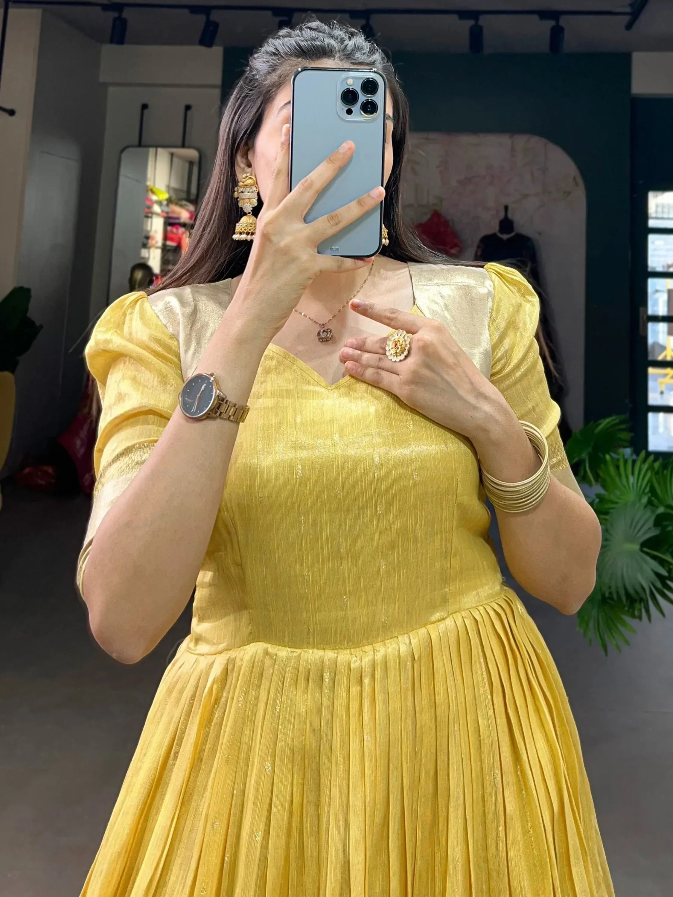 Yellow ethnic gown with pleated skirt, puff sleeves, and gold jewelry for festive occasions