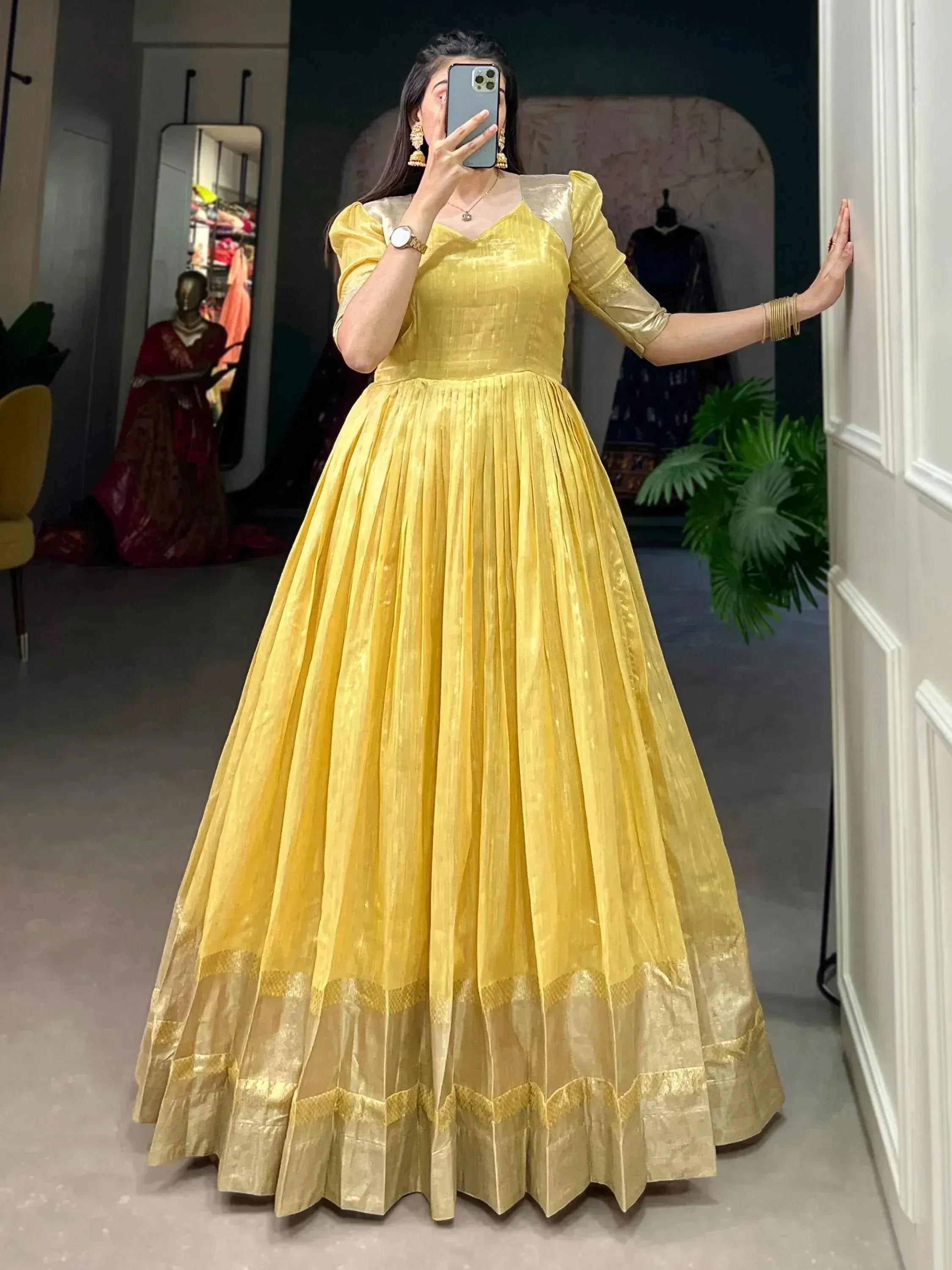 Yellow ethnic gown with pleated skirt and gold trim, perfect for Indian occasions and festive wear.