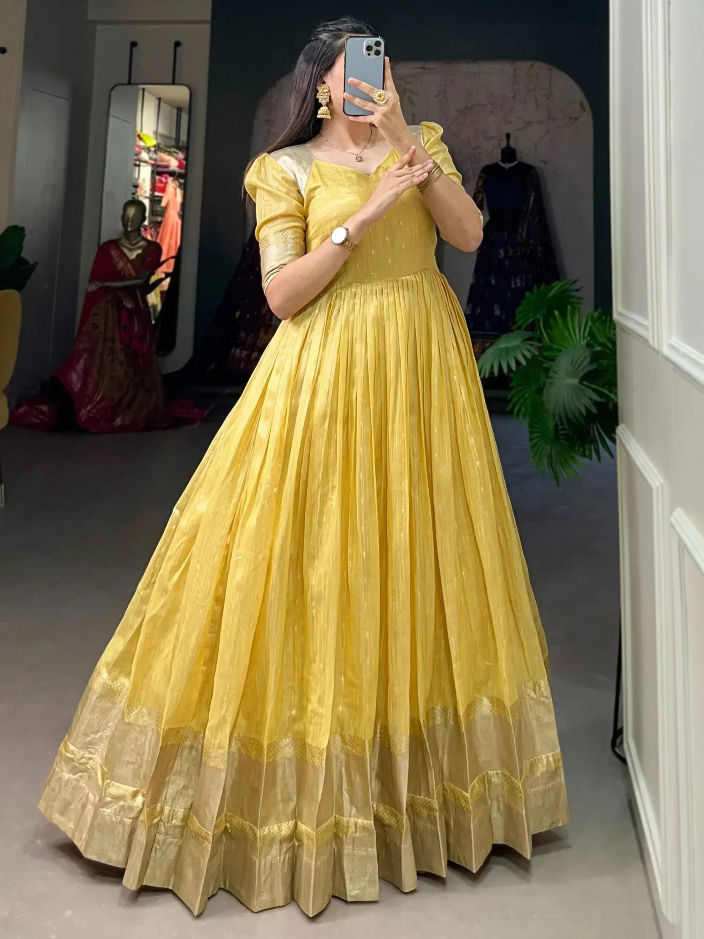 Yellow ethnic gown with pleated skirt and gold trim, perfect for Indian occasions