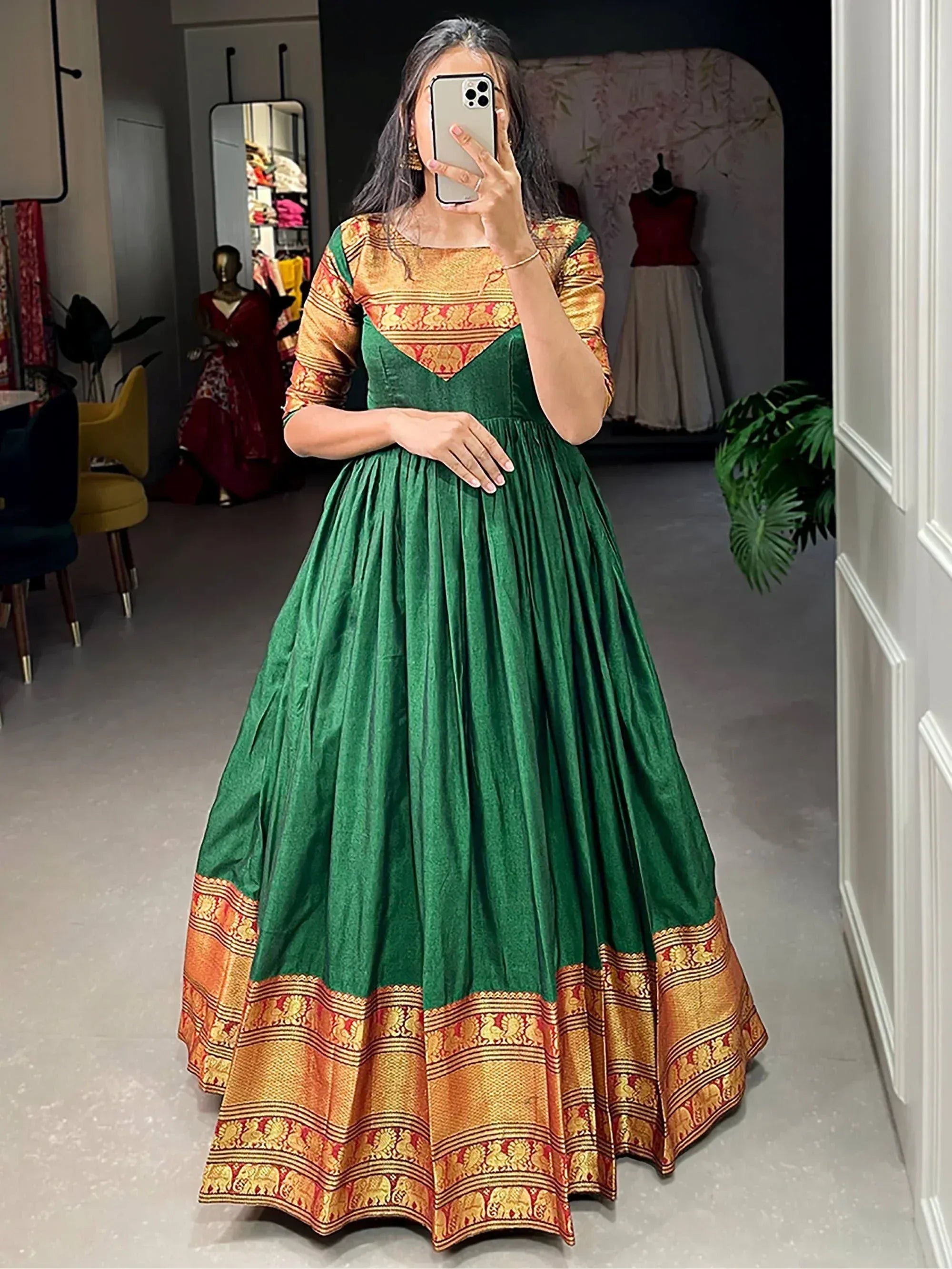 Green velvet ethnic gown with gold and red Banarasi border, perfect for Indian celebrations