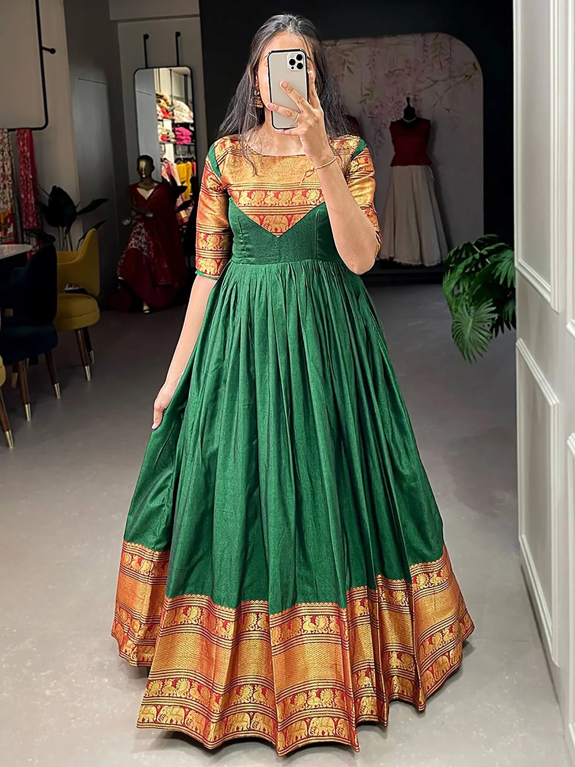 Green velvet ethnic gown with gold brocade border, perfect for Indian occasions and festive wear.